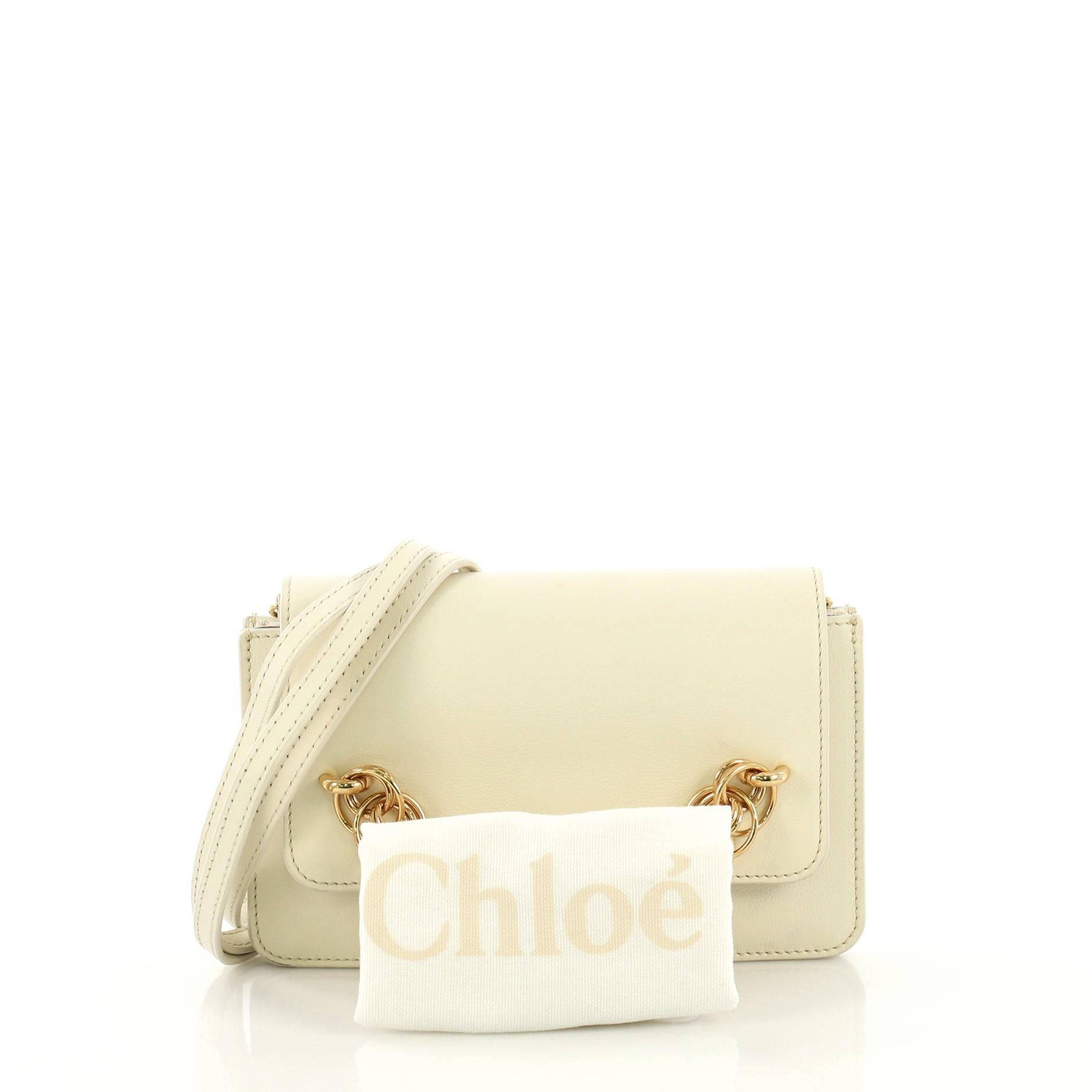 This Chloe Drew Bijou Clutch Leather, crafted in neutral leather, features a removable leather strap, bracelet-inspired chain link on its flap, and gold-tone hardware. Its magnetic snap closure opens to a neutral suede interior with three open
