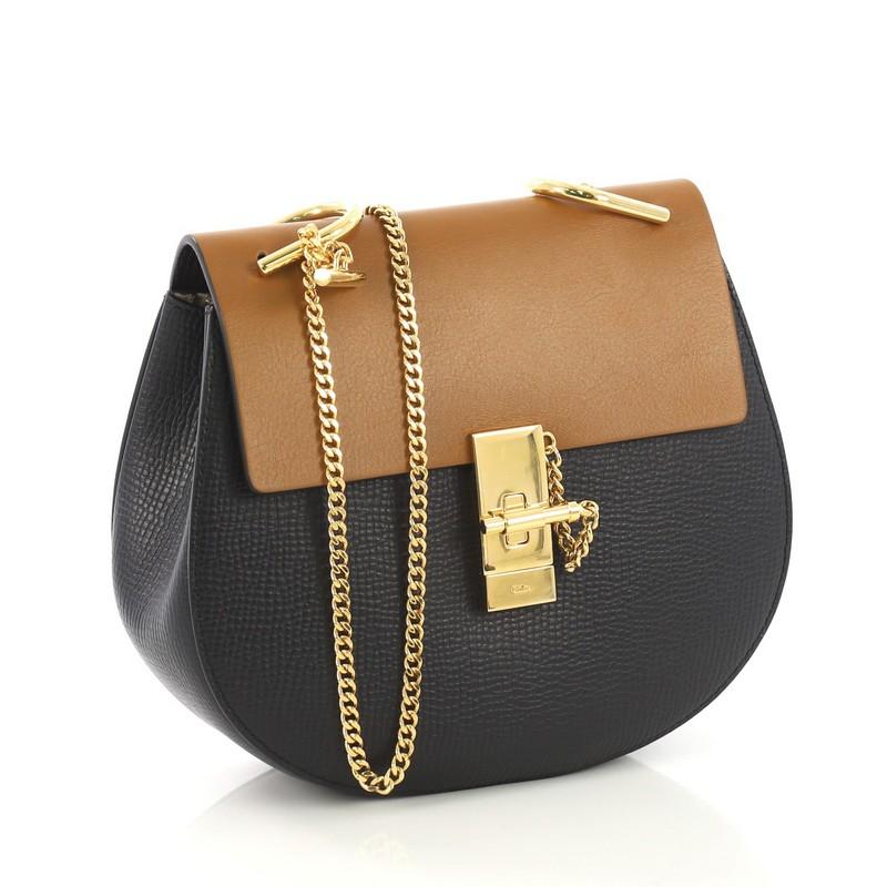 This Chloe Drew Crossbody Bag Leather Small, crafted in dark navy and brown leather, features a long chain strap accented with oversized U-shaped rings and gold-tone hardware. Its oversized turn-lock closure opens to a nude suede interior with patch