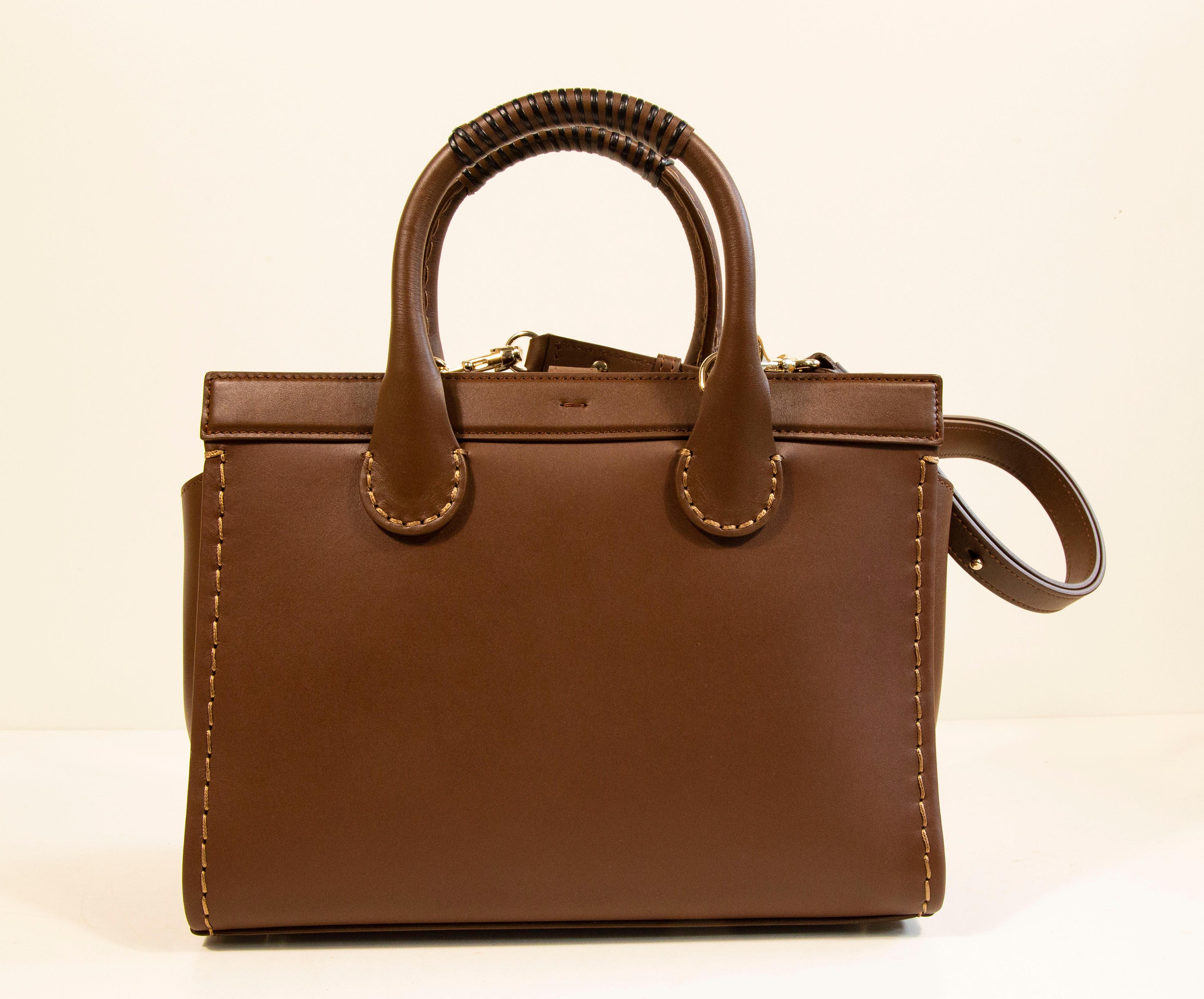 Chloe Edith Medium Tote Bag aus mokkabraunem Leder. Die Tasche ist aus Kalbsleder gefertigt und mit goldfarbenen Beschlägen versehen. Die Tasche kann an den beiden oberen Griffen als Henkeltasche oder mit dem abnehmbaren Schulterriemen als