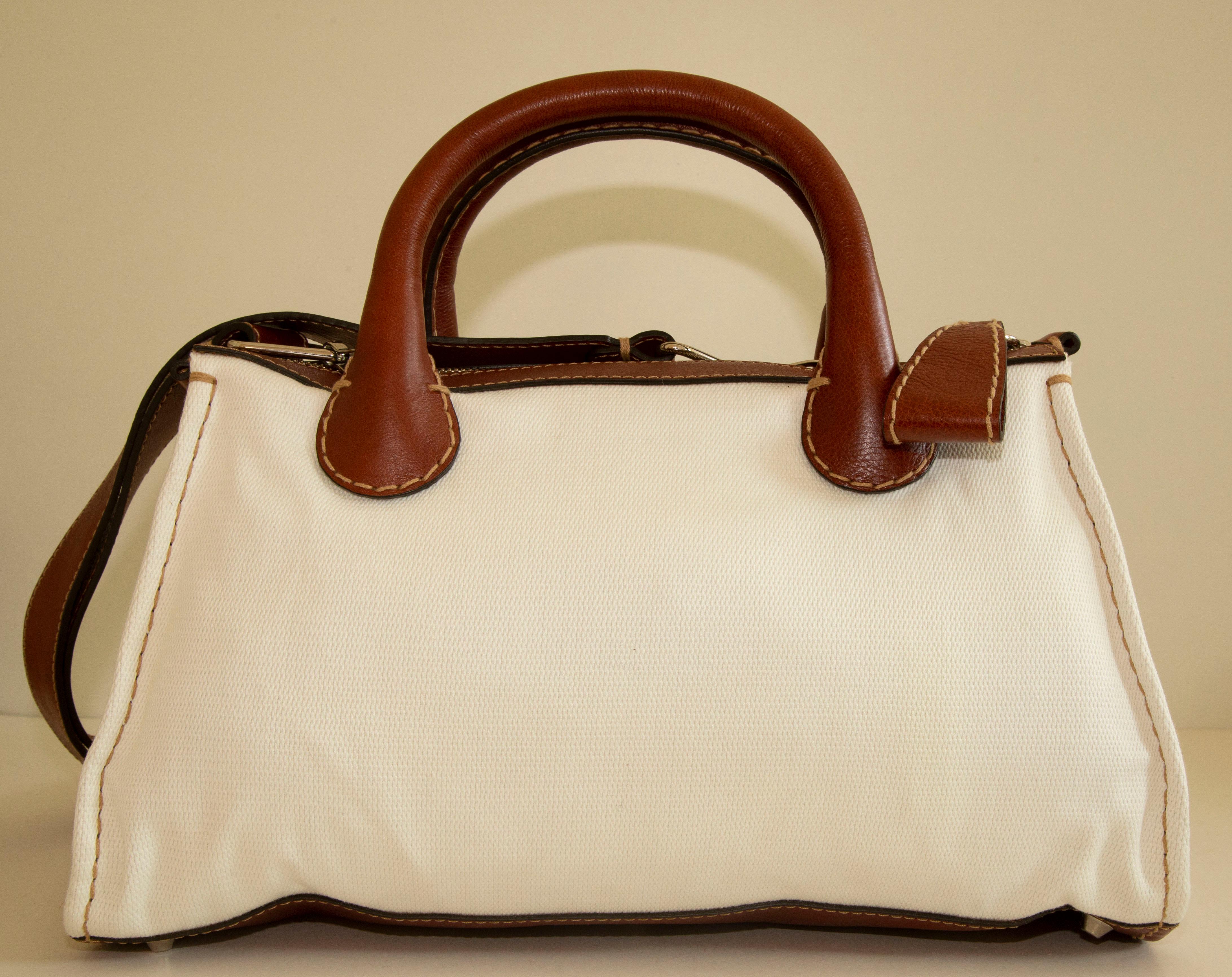 Chloe Edith medium tote made of white canvas with brown leather trim and silver tone hardware. The bag can be worn as a top handle bag or as a shoulder bag with the detachable shoulder strap (108 cm long). The interior is lined with brown fabric and