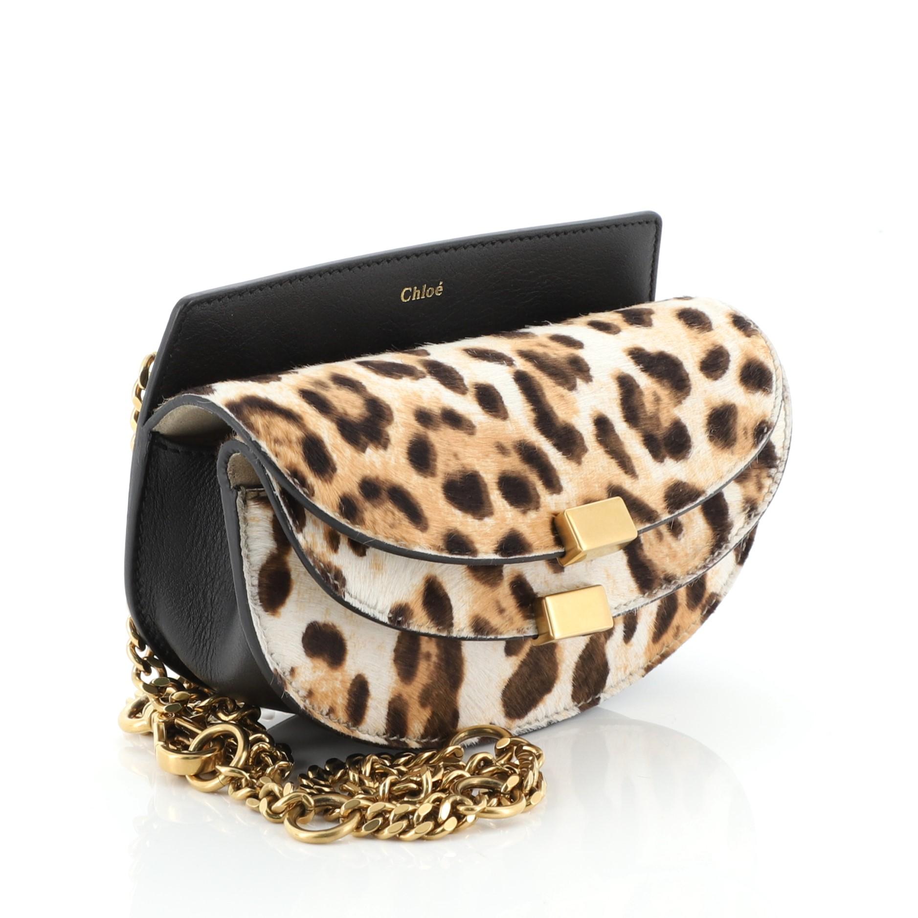 This Chloe Georgia Belt Bag Printed Pony Hair, crafted in black leather and printed pony hair, features chain-link strap and mate gold-tone hardware. Its snap closure opens to a neutral suede interior. 

Estimated Retail Price: $1,070
Condition: