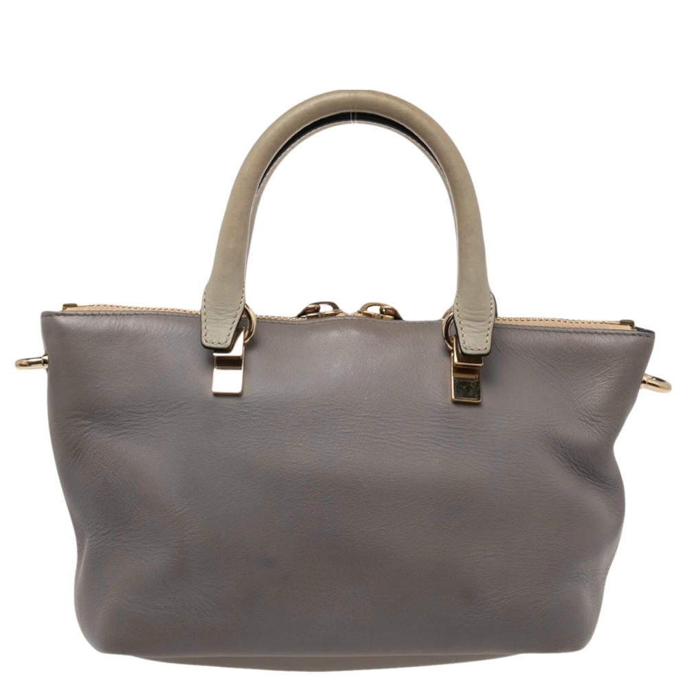 Die Baylee-Tasche ist eine der vielen beliebten Taschen von Chloe. Es hat ein minimalistisches Design, aber sehr interessante Details. Das glatte, grau-beigefarbene Leder ist mit gerollten Griffen, einer goldfarbenen Kette und einem abnehmbaren