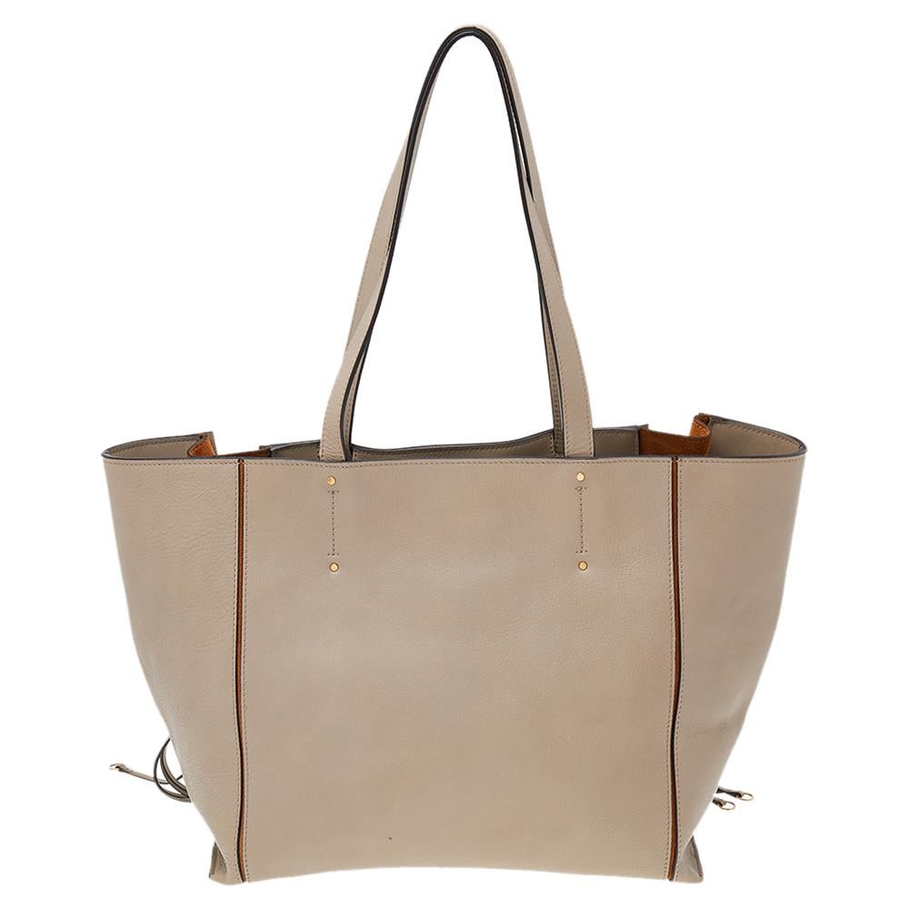 Effortlessly carry all your essentials in style with this Milo tote from Chloe. It is made using grey-brown leather and suede on the exterior with gold-toned hardware, perceptible stitch detailing, and zipper accents highlighting its shape. Give