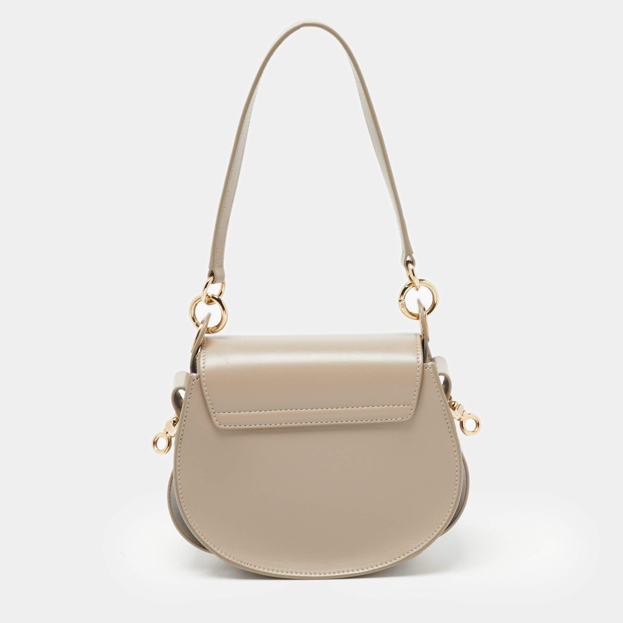 From the saddle shape to the gold-tone metal accents on the front, this Tess bag from Chloe is statement-making. It is crafted from leather and suede with a handle and a shoulder strap. The interior is lined with fabric.

Includes: Original Dustbag,