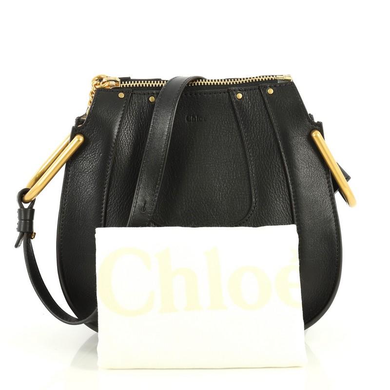 This Chloe Hayley Hobo Leather Mini, crafted from black leather, features an adjustable shoulder strap, chain insets, saddle-shaped silhouette, and gold-tone hardware. Its zip closure opens to a neutral suede interior divided into two compartments
