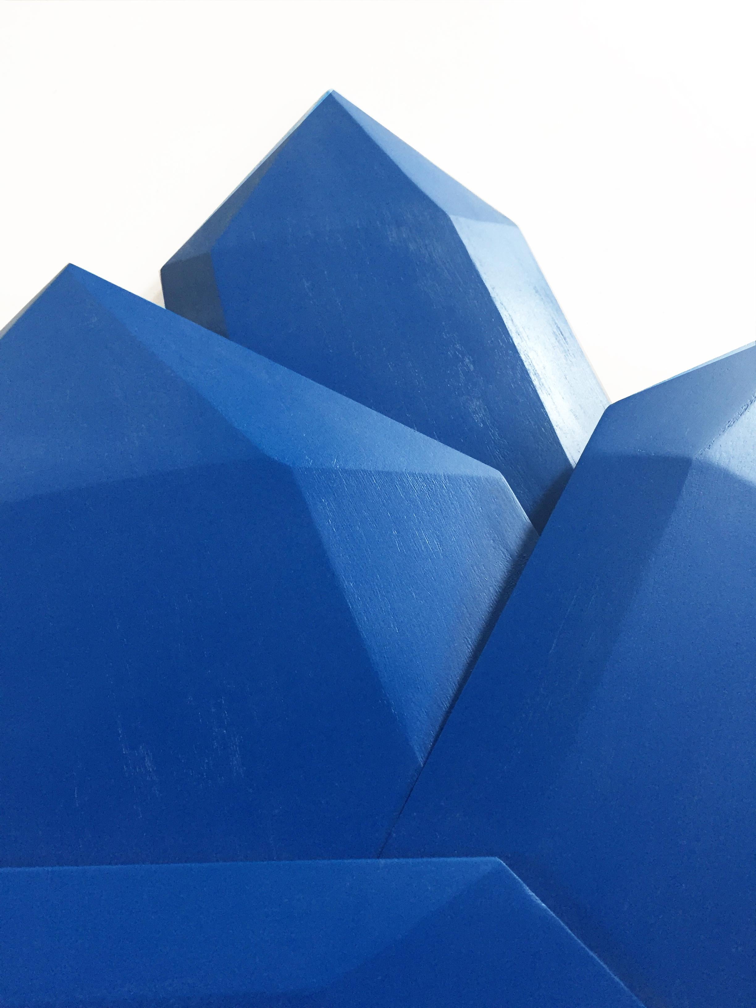 “True Blue Crystals” is a bright sapphire blue wall sculpture made out of solid wood and then painted and sealed with a UV matte sealer. The geometric facets are hand carved and add intricacy to the structure. This creates a dynamic artwork where