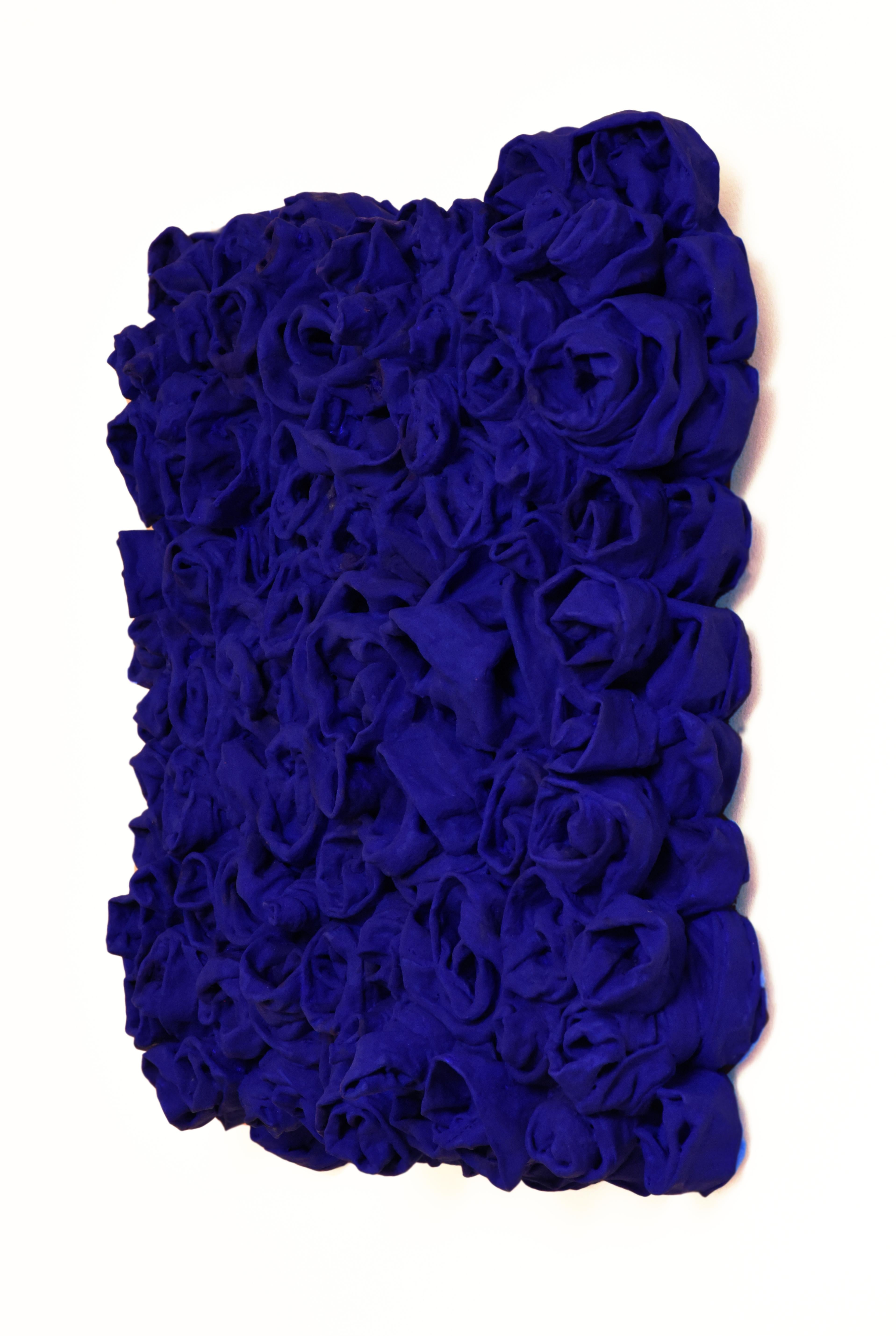 “Ultra Blue Rosettes” is a vivid blue wall sculpture made with fabric on linen. The elegant folds are steadily built up and add intricacy to the structure. This creates a dynamic artwork where light circulates on the surface and shadows are