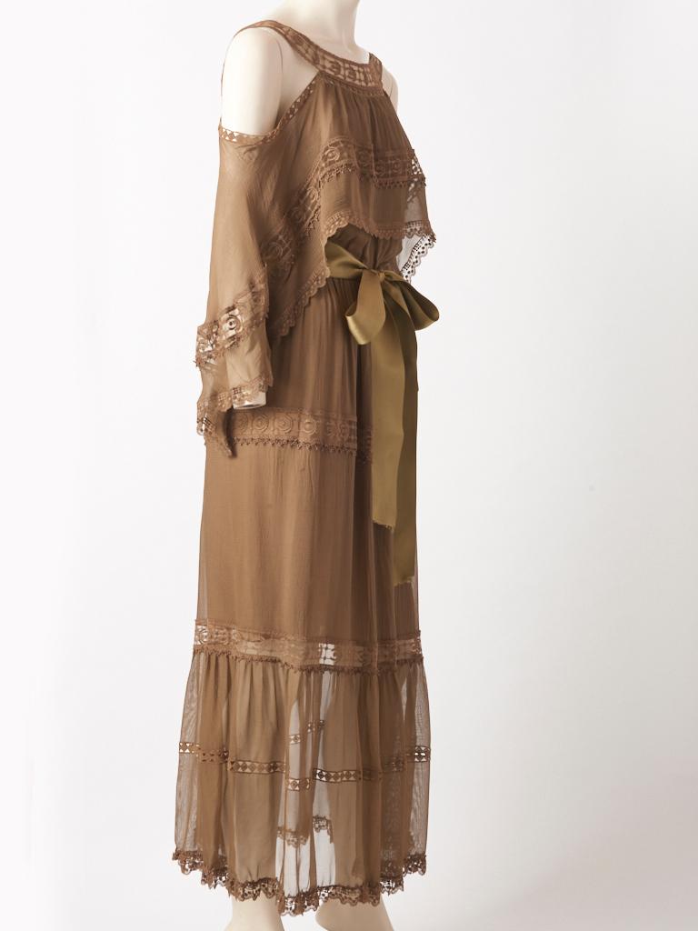Chloe, khaki tone, georgette and lace,  maxi dress having a tiered, cape-like panel at the bodice, acting as a loose sleeve, but exposing the shoulders with intricate, scalloped lace trim detail. Skirt is tiered having horizontal, bands of lace at