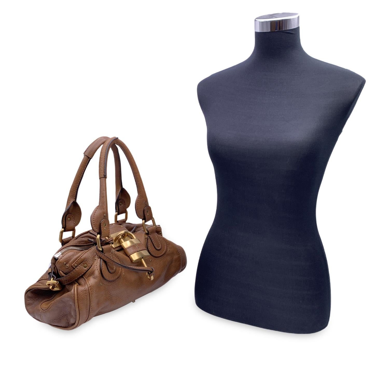 Gorgeous CHLOE Paddington Bag' crafted in genuine leather in light brown color. This bag features intense detailing such as chunky hardware, belting as well as two-rolled leather handles. At the front of the bag you will find the classic Chloe