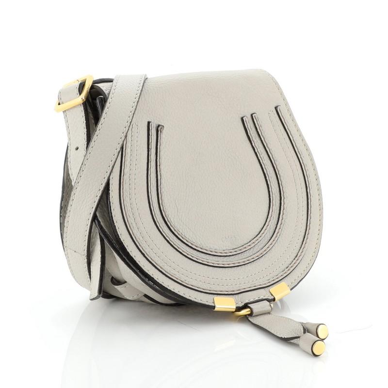 This Chloe Marcie Crossbody Bag Leather Small, crafted from gray leather, features stitched horseshoe detail on the front, adjustable strap, and aged gold-tone hardware. Its flap opens to a green fabric interior with slip pocket. These are