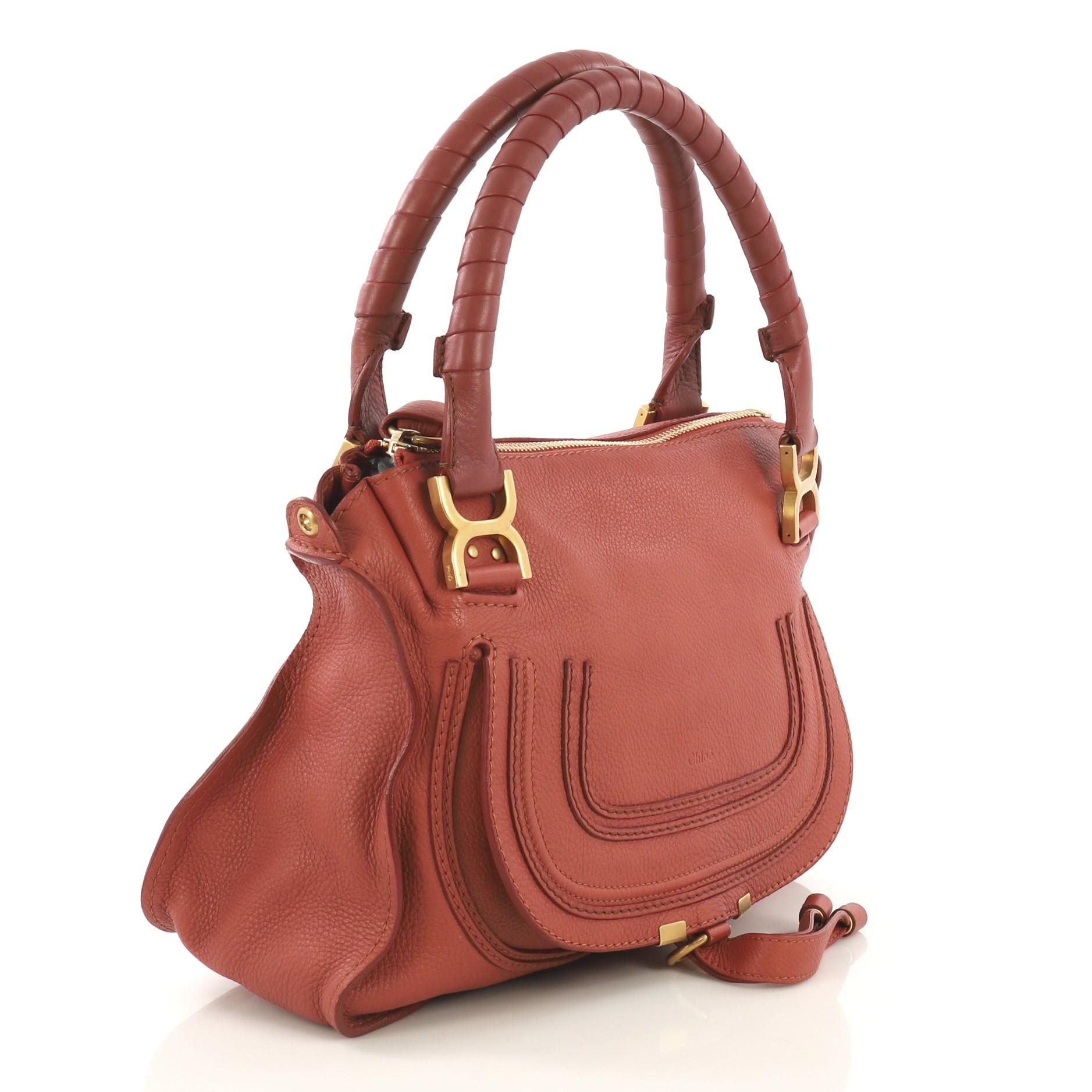 This Chloe Marcie Satchel Leather Medium, crafted in coral leather, features wrapped leather handles, horseshoe stitched on front flap, and gold-tone hardware. Its top zip closure opens to a green fabric interior with zip and slip pockets.