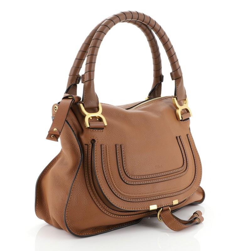 This Chloe Marcie Satchel Leather Medium, crafted in brown leather, features wrapped leather handles, horseshoe stitched front flap, and aged gold-tone hardware. Its top zip closure opens to a green fabric interior with zip and slip pockets.