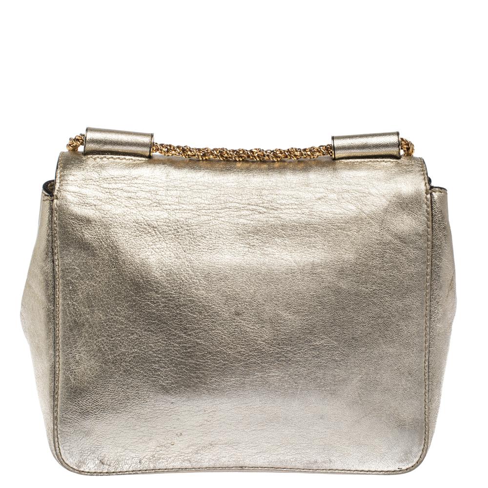 Every curve and detail on this Chloe Elsie is grand which adds to the worth of the bag. It has been crafted from metallic gold leather and styled with a flap. The bag is secured by a turn-lock revealing a well-sized interior and completed with a top