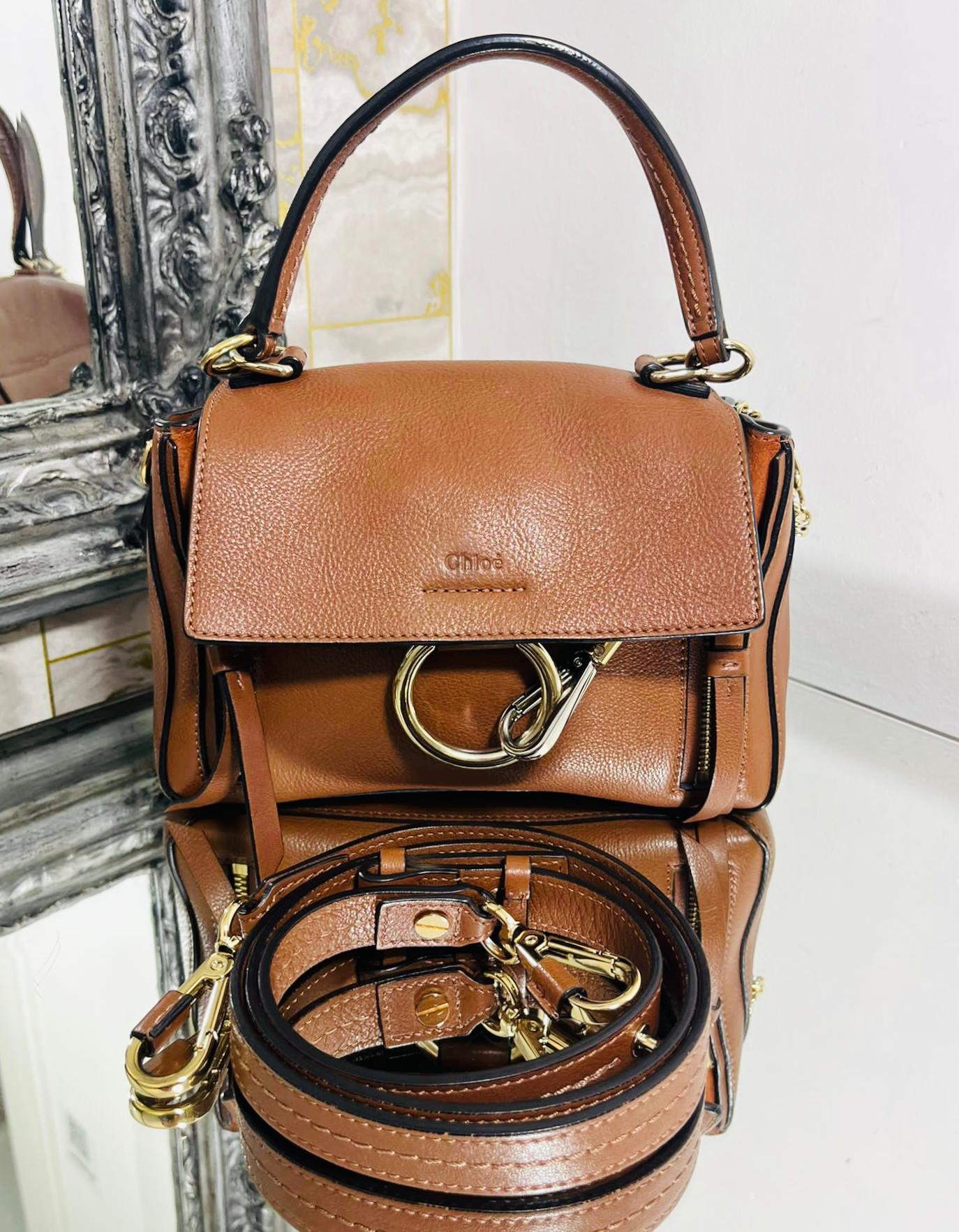 Chloe Mini Faye Day Leather Bag

Tan/brown handbag designed with front magnetic flap and embellished with double zips with leather pullers.

Featuring the line's signature ring loop and hanging chain to one side with gold and silver