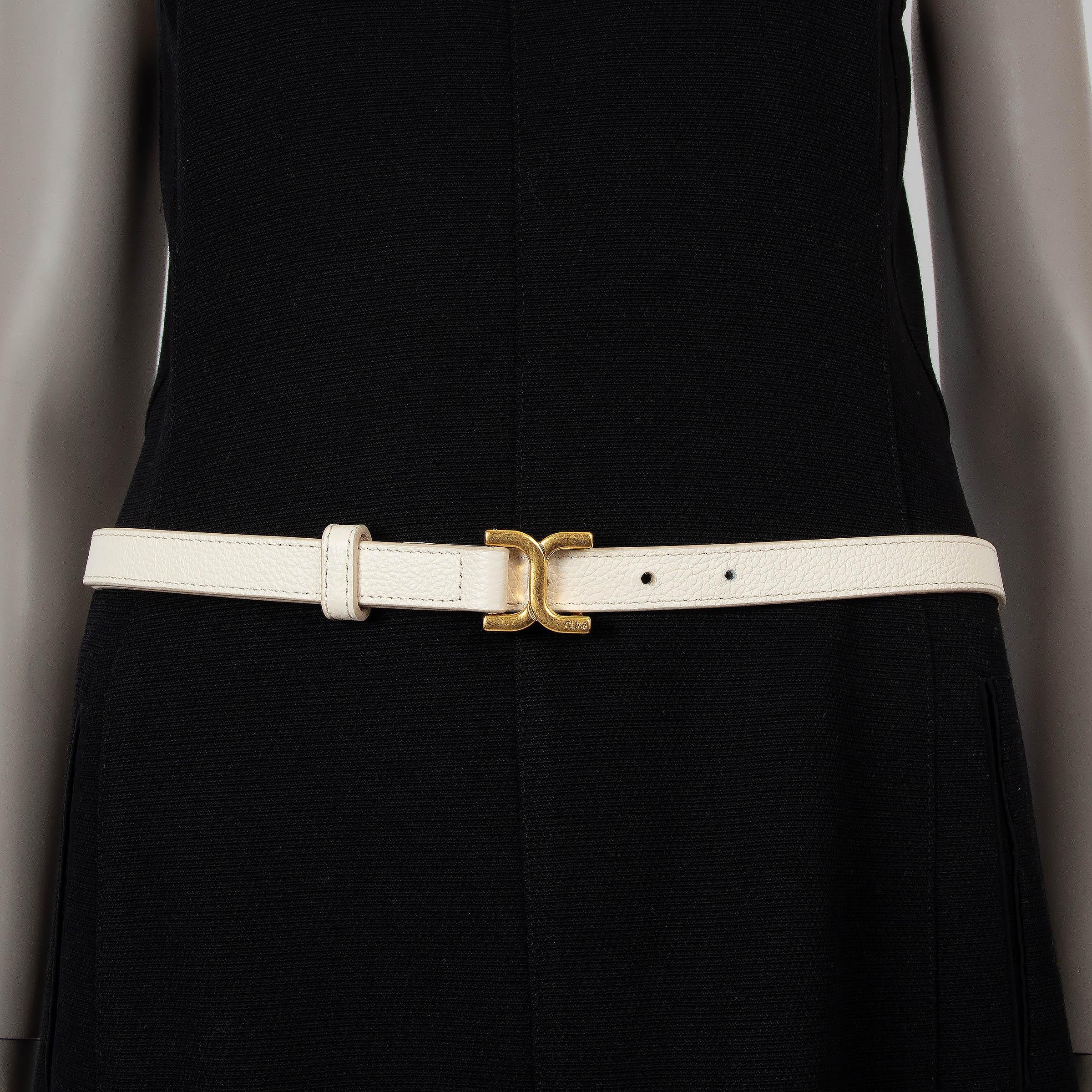 This 100% authentic Chloé logo belt is crafted from grained leather in a chic Misty Ivory hue, exuding understated elegance. Featuring gold-tone hardware, including a subtle engraved Chloé logo, this belt is the perfect accessory to add a touch of