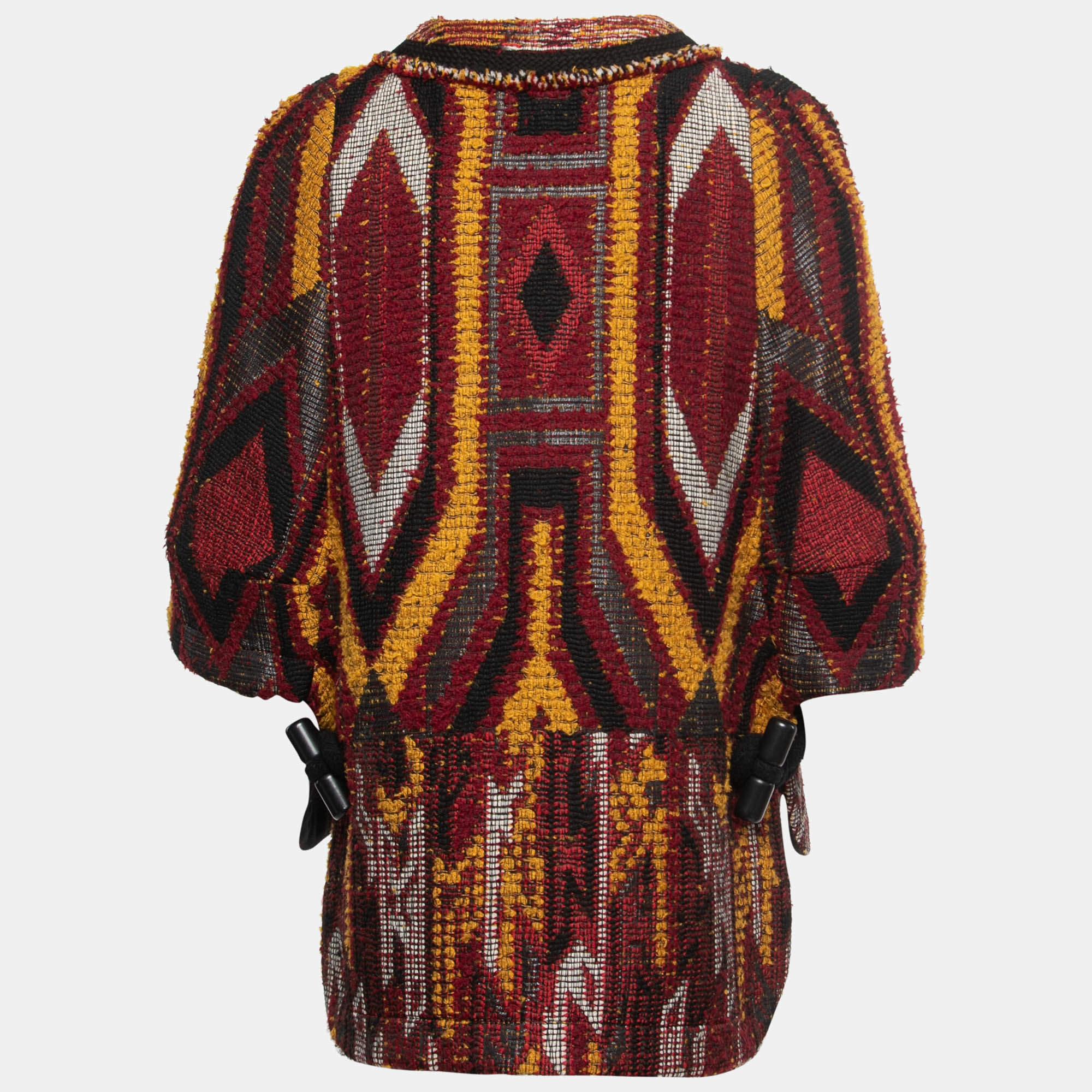 The Chloé coat is a stunning outerwear piece that combines style and warmth. This cape coat features a vibrant multicolor tribal pattern woven into a textured boucle tweed fabric. With its relaxed cape silhouette and intricate design, it's a fashion