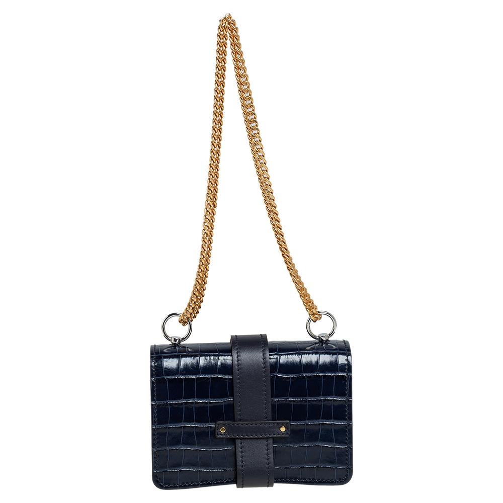 With an affinity to create chic bags that look like works of art, Chloe brings this Aby Lock bag that is just a masterpiece. Crafted from croc-embossed leather, it presents itself in a navy blue hue. It is styled with a front flap that carries a