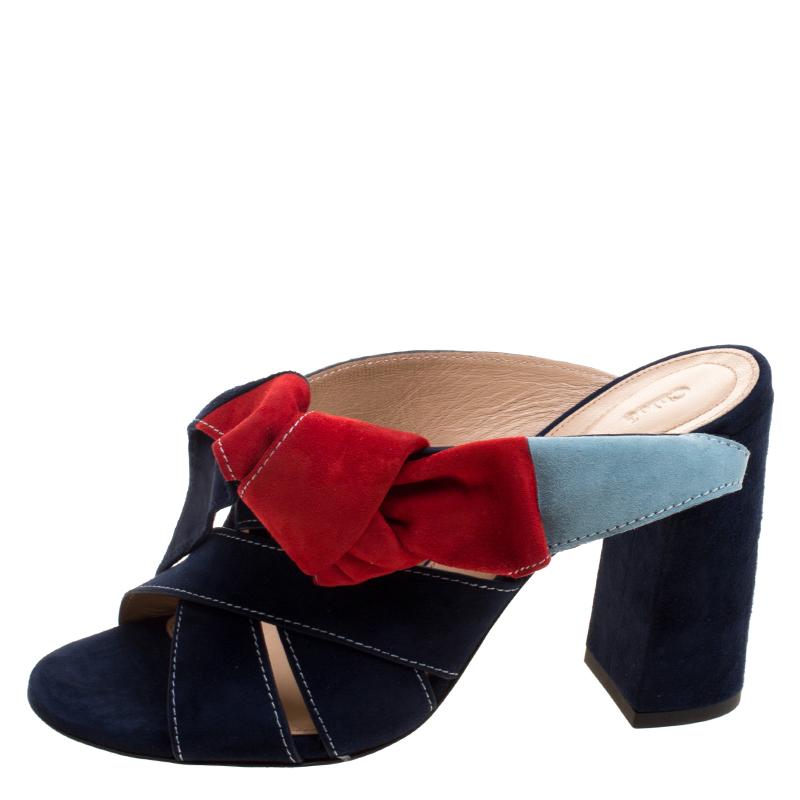 Step out with a bounce in your step in the Chloe Navy Blue Suede Nellie Bow Mules. The suede material is lined with leather, for optimal comfort. The contrast topstitching and the colour block trim, combined with the covered block heel gives a very