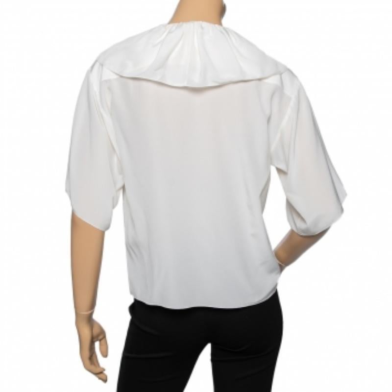 Questa blusa della Maison Chloe è l'incarnazione della bellezza e del portamento! È realizzato su misura in tessuto di seta bianco sporco, con un bordo increspato che sottolinea la sua silhouette. Ha un dettaglio di cravatta sulla scollatura.