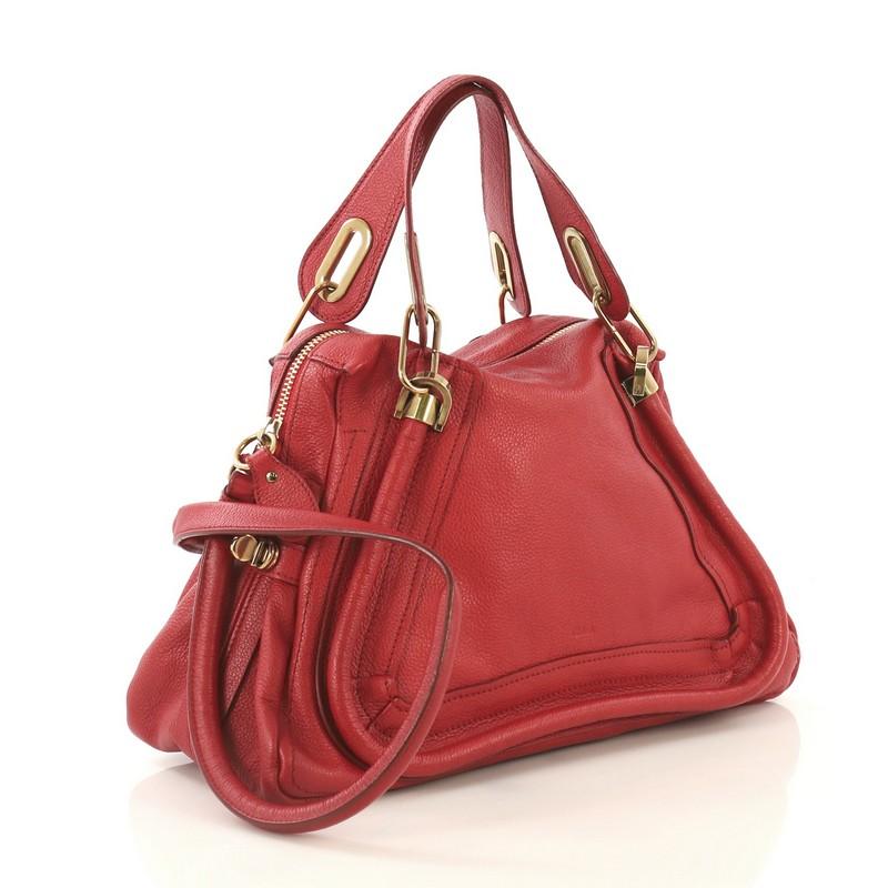 This Chloe Paraty Top Handle Bag Leather Medium, crafted in red leather, features dual flat leather handles, piped trim details, and gold-tone hardware. Its top zip closure opens to a neutral fabric interior with zip and slip pockets. 

Estimated