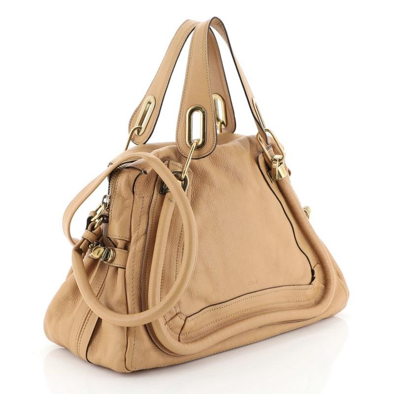 This Chloe Paraty Top Handle Bag Leather Medium, crafted in brown and neutral leather, features dual flat leather handles, piped trim details, and gold-tone hardware. Its zip closure opens to a neutral fabric interior with zip pocket. 

Condition: