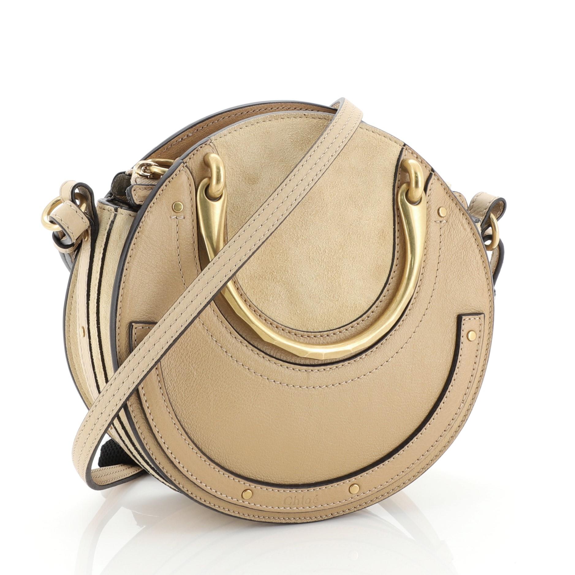 This Chloe Pixie Crossbody Bag Leather and Suede Small, crafted in neutral leather, features dual matte gold handles, round silhouette and matte gold-tone hardware. Its zip closure opens to a neutral suede interior with slip pocket. 


Estimated