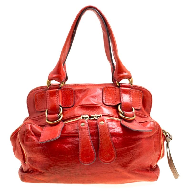 This satchel from Chloe will make a truly luxurious addition to your collection. Crafted from red leather the bag features double top handles and two zip pockets on the exterior. It has a top zipper that opens to reveal a fabric interior for your