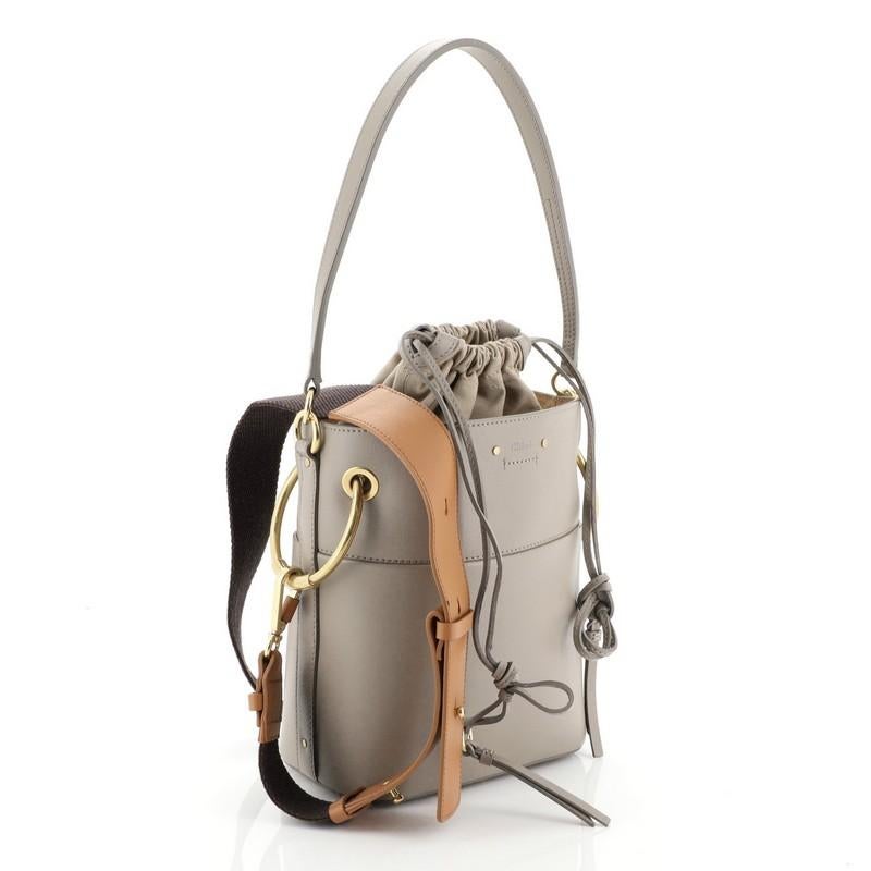 This Chloe Roy Bucket Bag Leather Small, crafted in gray leather, features a leather shoulder strap, oversized rings and gold-tone hardware. It opens to a neutral fabric interior with zip pocket. 

Estimated Retail Price: $1,800
Condition: Great.