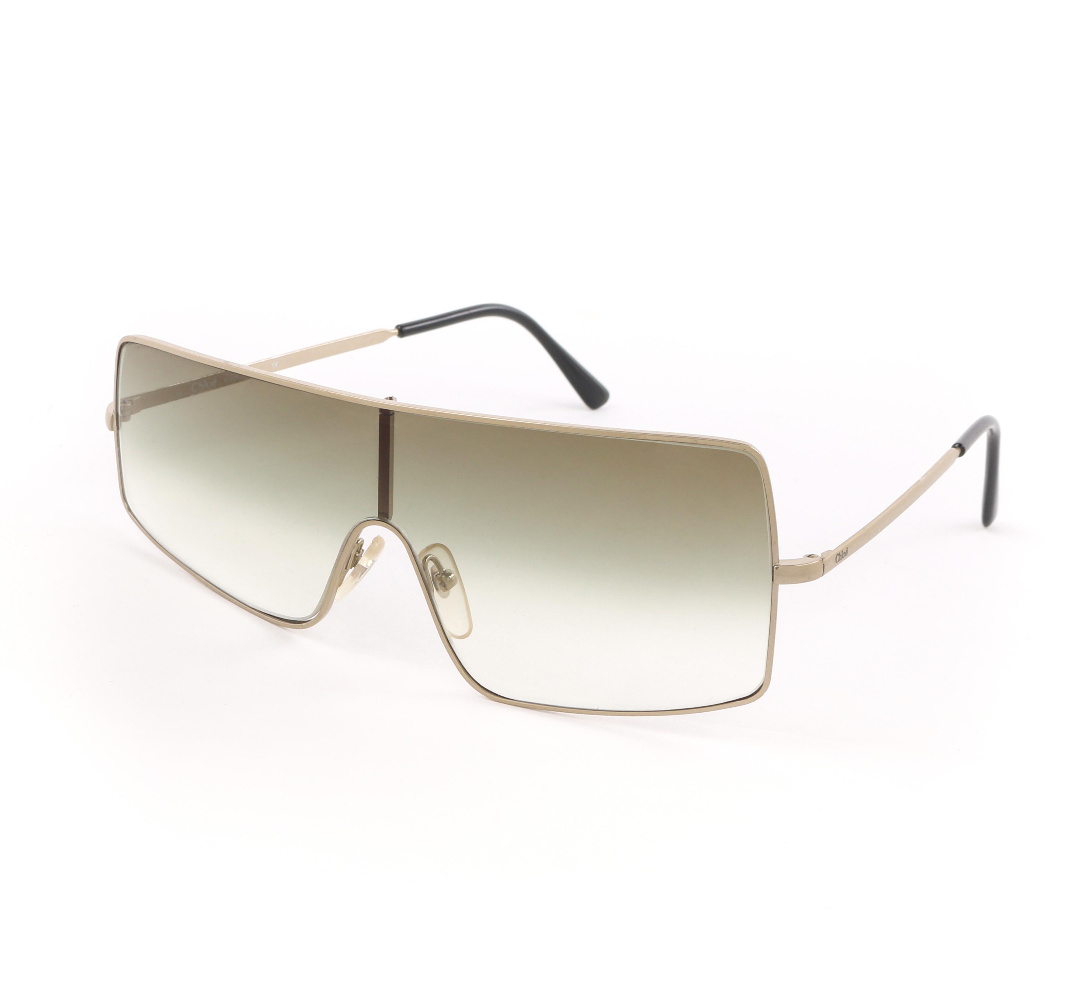 DESCRIPTION: CHLOE S/S 2001 Gold Asymmetrical Wire Frame Shield Sunglasses 76S
 
Brand / Manufacturer: Chloe
Collection: Spring / Summer 2001
Designer: Stella McCartney 
Style: Shield sunglasses
Color(s): Shades of gold and green
Unmarked Material