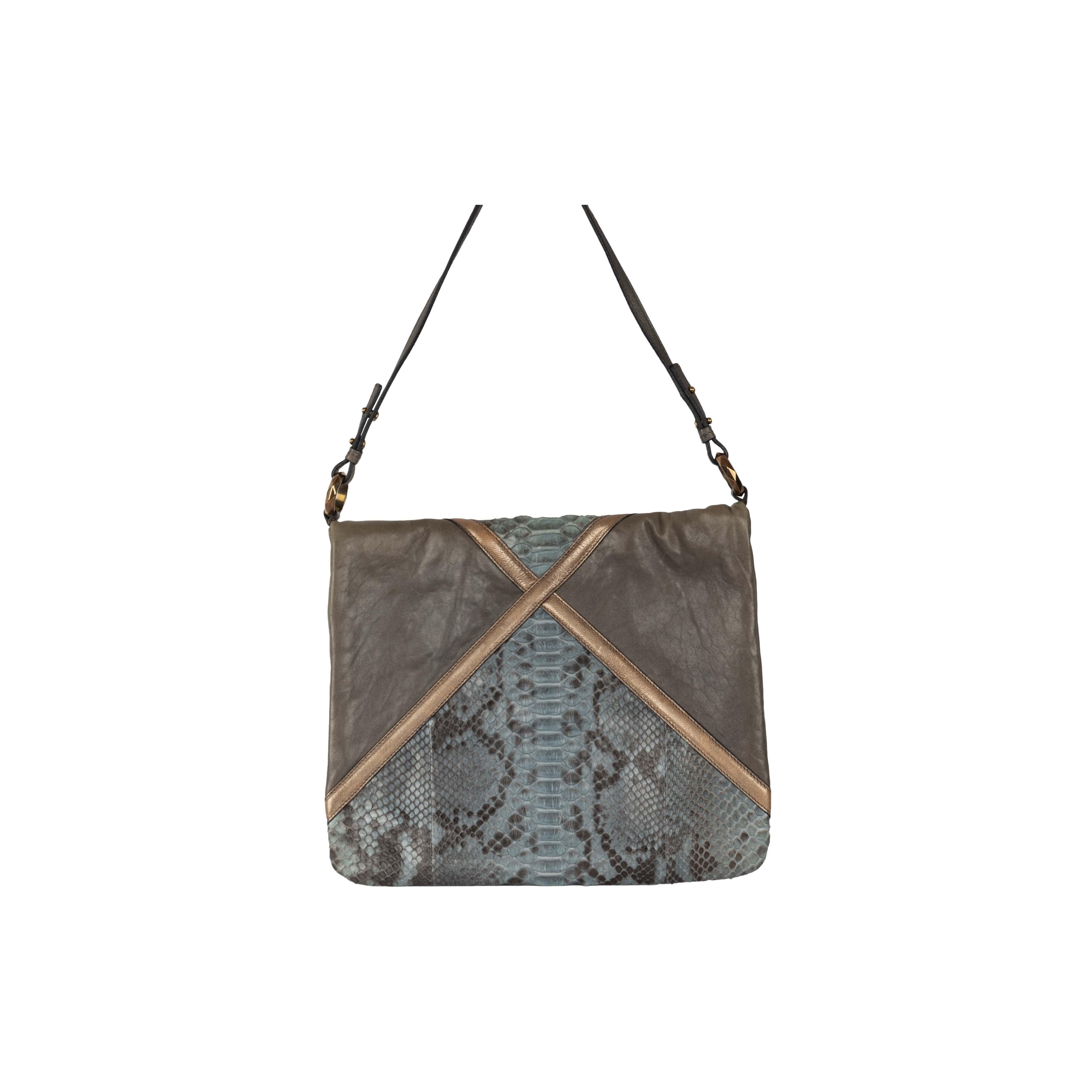 The Chloe Snakeskin Envelope Bag is a textural masterpiece with a unique combination of grey leather, snakeskin leather, and a bronze ribbon separating them and creating a symmetrical illusion. The bag can be closed with a snap