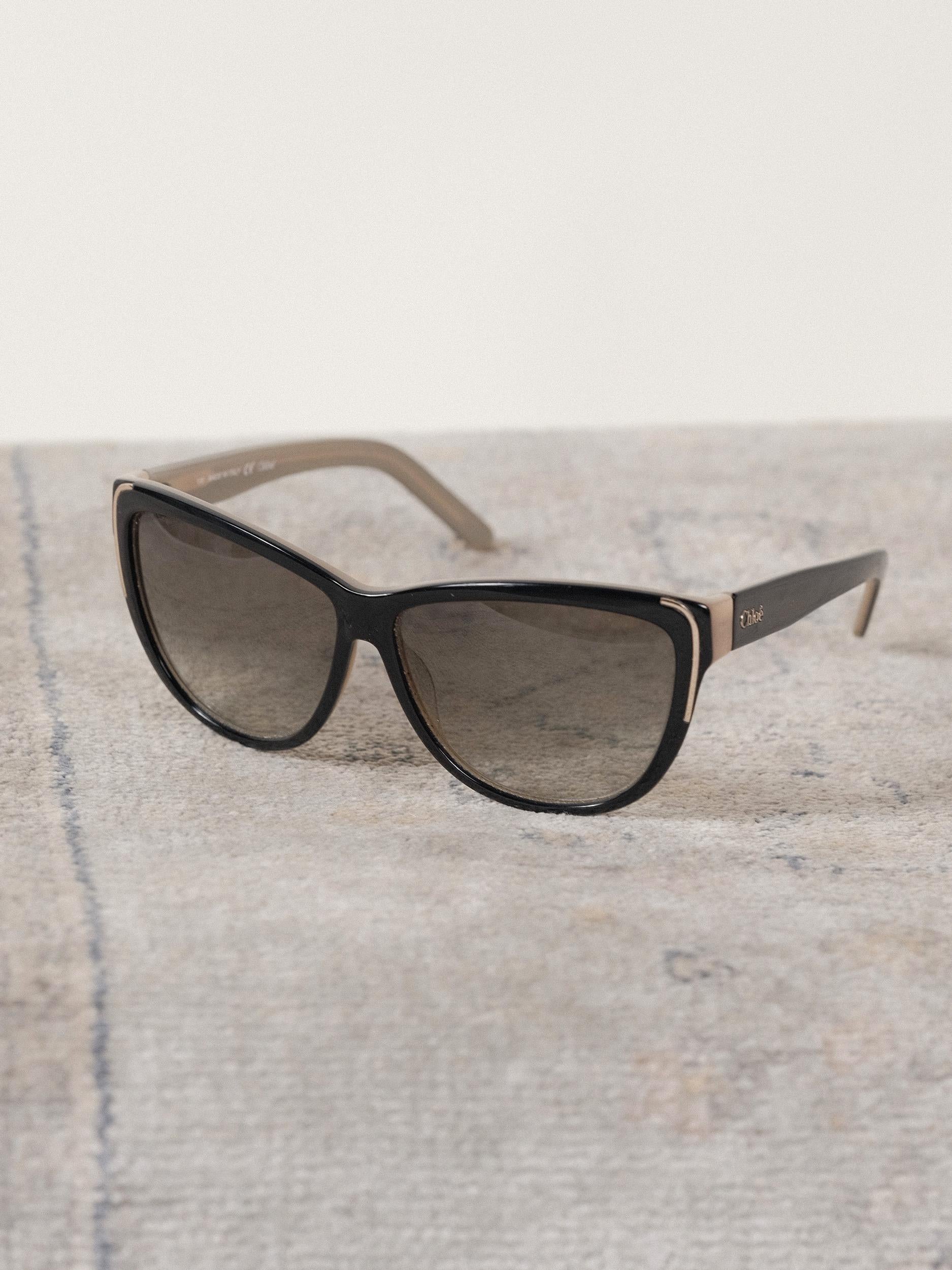 Chloé Sunglasses
Cat Eye, Greenish Neutral Gradient Lens 
Circa 2000's
Black and Taupe with Gold Detail
Signature logo on arm 
14cm/5.5in across (temple to temple)
Height- 5cm/2in
Eye Size - 59mm
Includes Original Case 