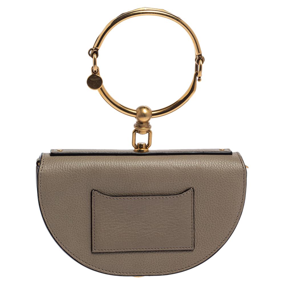 This Nile bag by Chloe can become your most favorite bag, thanks to its unique shape and bracelet handle. This crossbody bag has been crafted using taupe leather and styled with a front flap that opens to a leather-lined interior. It is complete