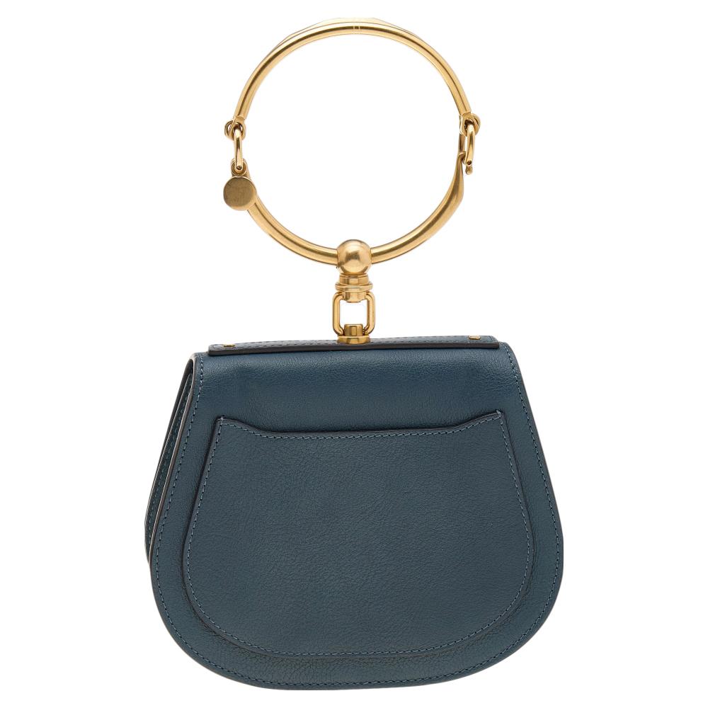 This Nile bag by Chloe can become your favorite bag, thanks to its unique shape and the bracelet handle. It has been crafted from teal blue leather as well as suede and styled with a front flap that opens to a suede interior. It is complete with a