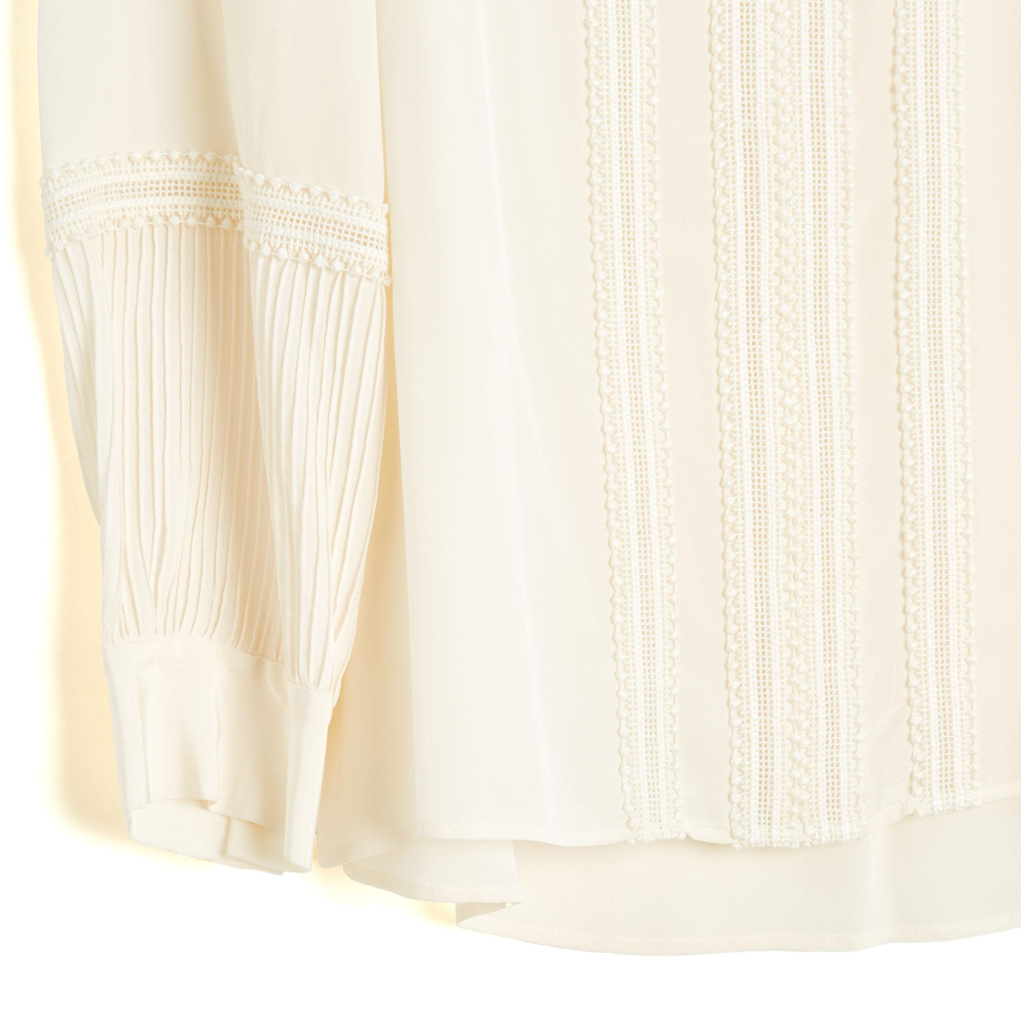 Top Chloé blouse in ecru silk crepe, straight cut, deep neckline closed by a jewel button (and an intermediate hook), chest and sleeves embroidered with an openwork crochet pattern, long slightly balloon sleeves closed by a button. Size 40FR: