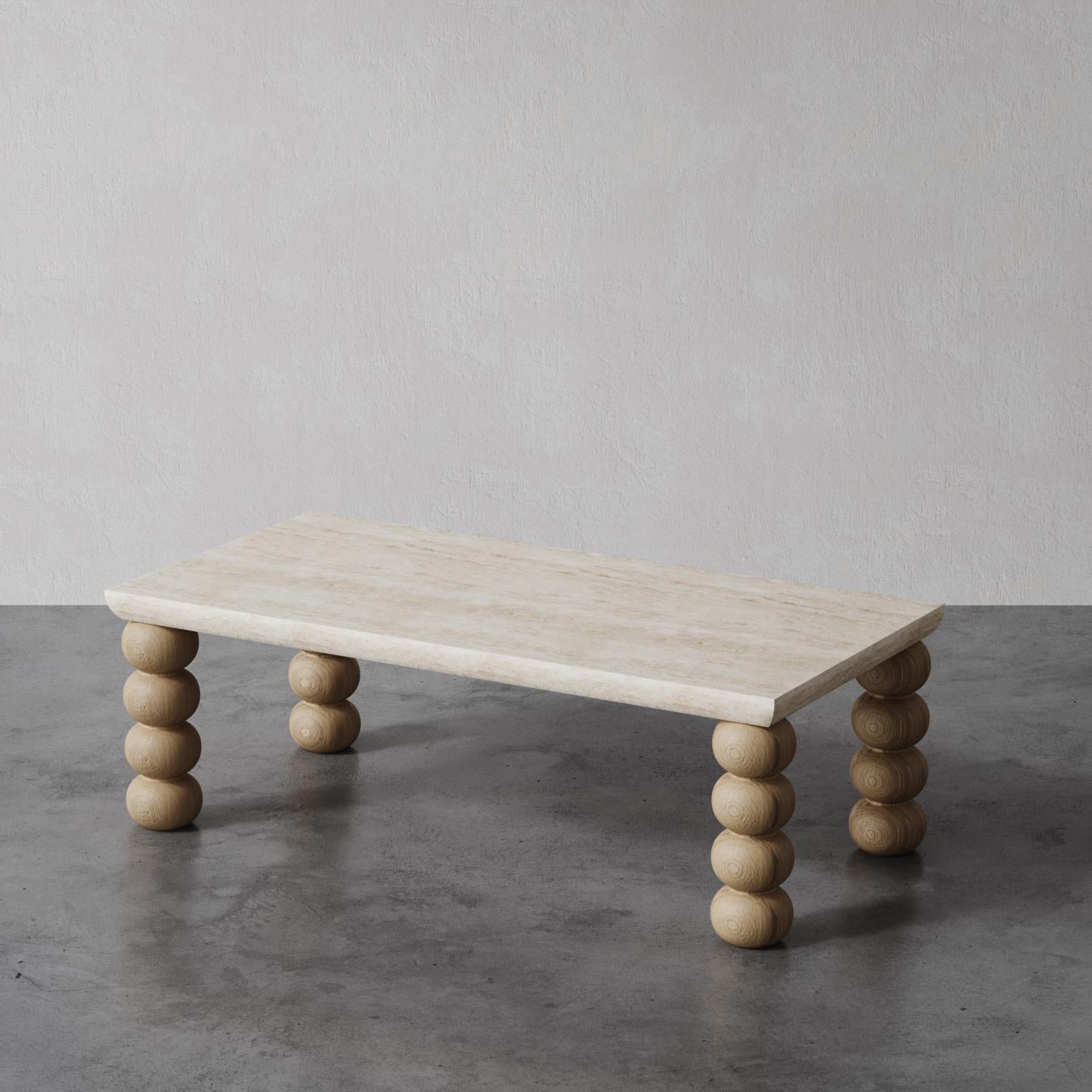 Il tavolino Chloé presenta un piano in travertino rettangolare di dimensioni generose con un profilo curvo, perfettamente completato da gambe in Oak massiccio tornite a mano. Le gambe ricordano quelle a forma di rocchetto del 1800, rivisitate in