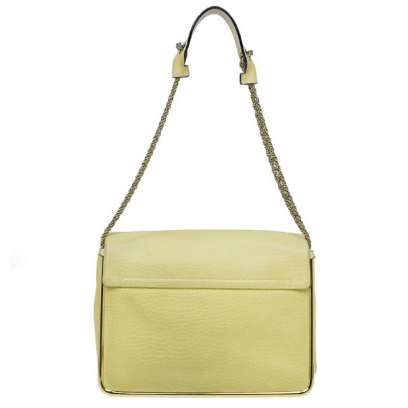 A striking yellow color, this Chloe shoulder bag is a feminine beauty. The pebbled leather exterior shines with its gold-tone hardware on the monogrammed clasp lock closure and flap. Its handle matches dark golden chains with a leather strap for