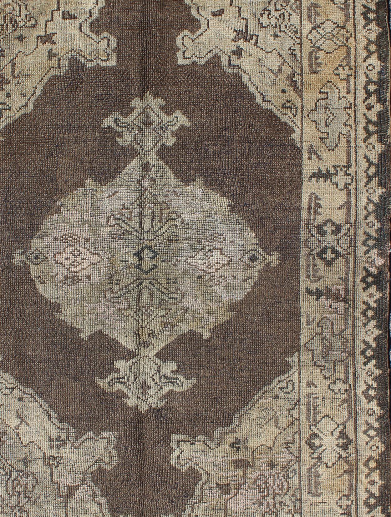 Chocolate background vintage Turkish Oushak rug with floral medallion in cream, Keivan Woven Arts / rug/TU-MOZ-08, country of origin / type: Turkey / Oushak, circa mid-20th century.

This vintage Turkish Oushak carpet (circa mid-20th century)