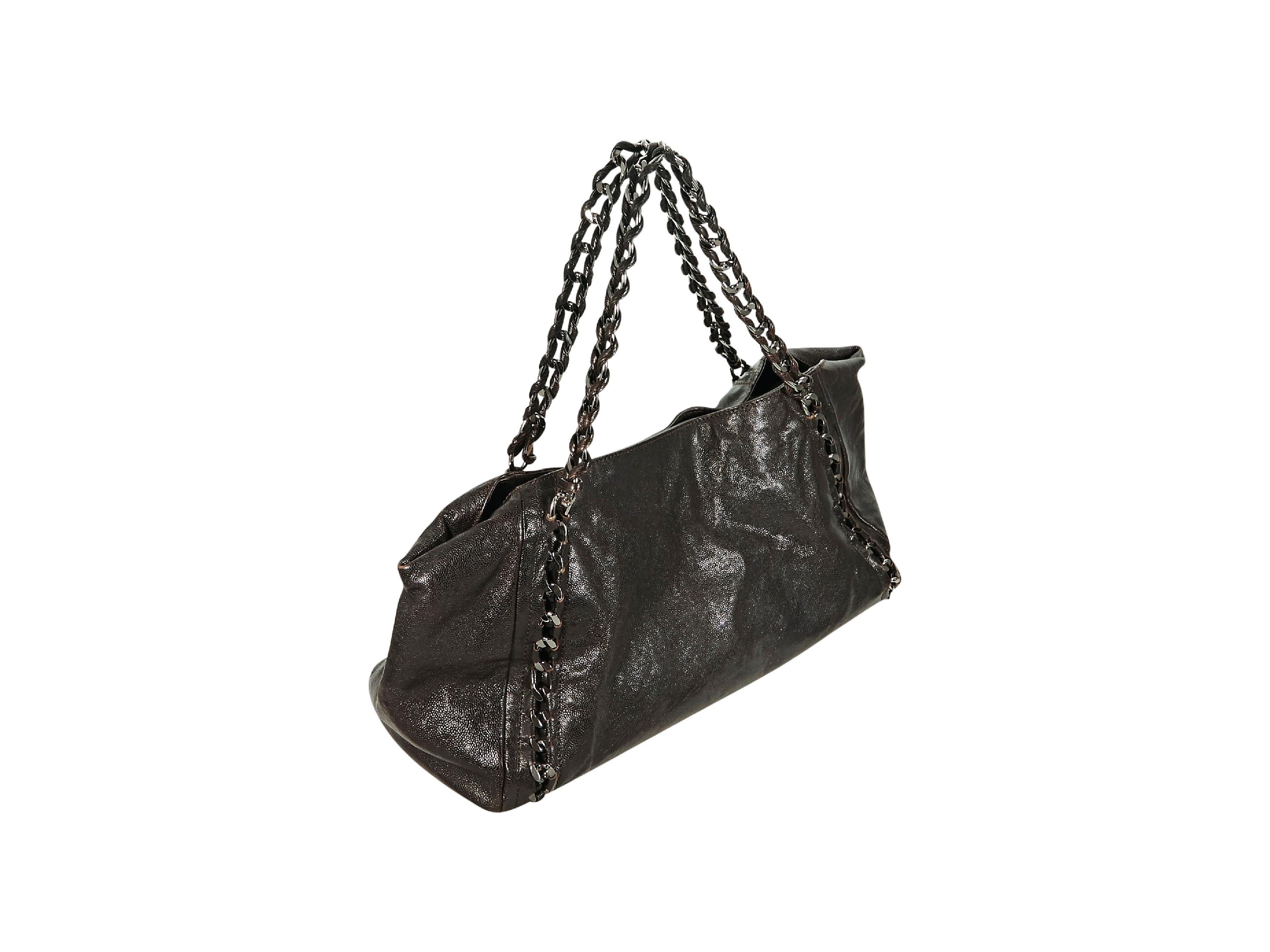 Product details:  Chocolate brown leather tote bag by Chanel.  Logo detail accents front.  Dual shoulder straps.  Top magnetic snap closure.  Lined interior with inner zip and slide pockets.  Protective metal feet.  Silvertone hardware.  21.5