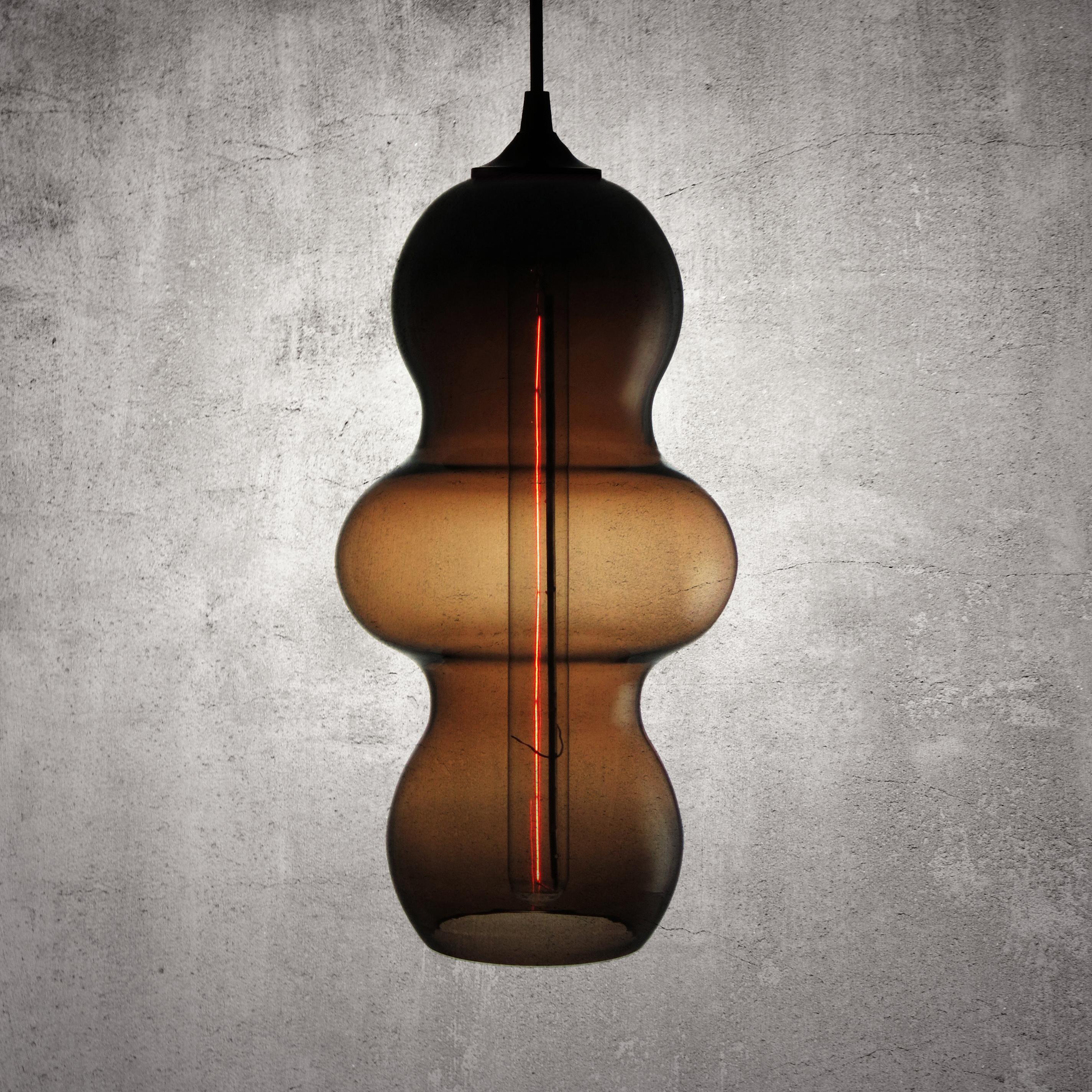 The Tamarindo contemporary glass pendant lamp is a contemporary interpretation of the tamarind fruit. Encapsulating its characteristics, the Tamarindo is sleek, curvaceous and light, hanging effortlessly with its long elongated form juxtaposed by a