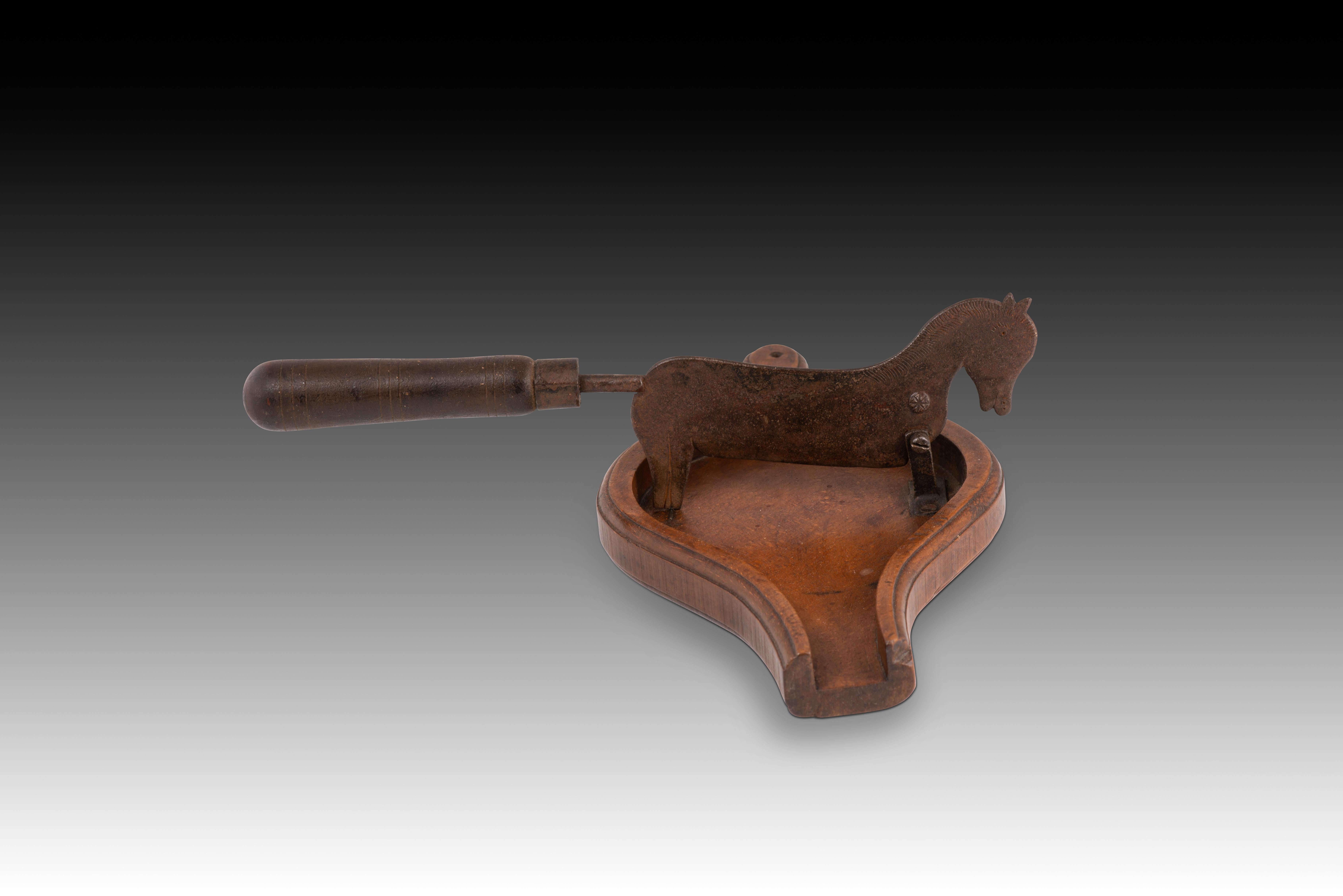  Schokoladenschneider. Holz, Metall. 19. Jahrhundert. 
 Schokoladenhacker aus geschnitztem Holz mit einer eisernen Klinge in Form eines Pferdes, die einen gedrechselten Holzgriff hat. Vergleiche mit dem im CIPE-Kostümmuseum in Madrid aufbewahrten