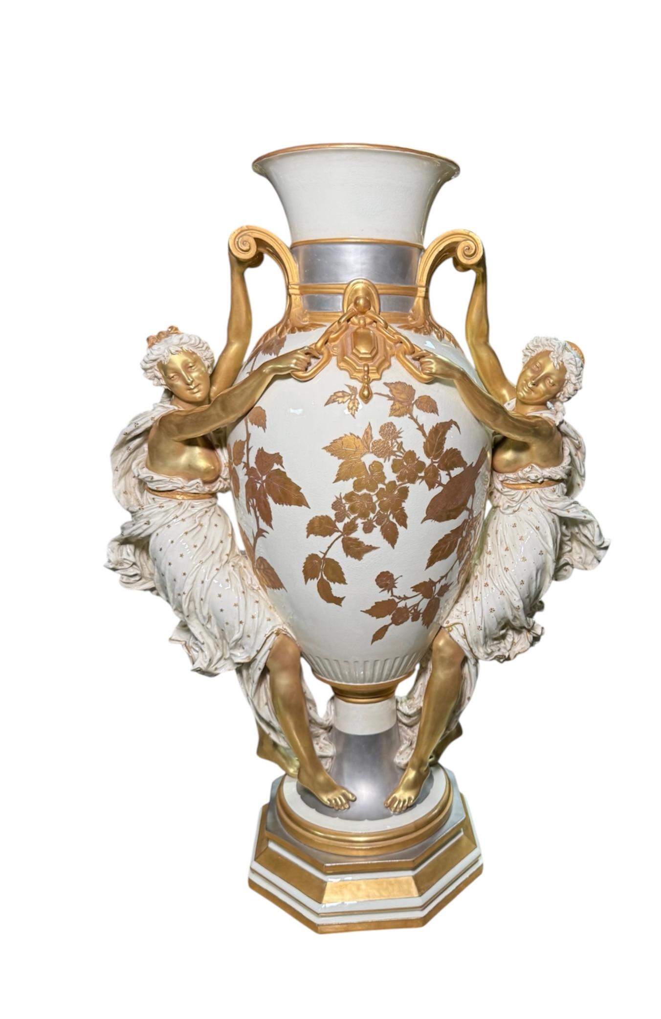 This is a Choisy le Roi Majolica Urn Vase after a model by Louis Robert Carrier Belleuse. It depicts a huge and heavy urn vase hand painted with a white background decorated with gold color leaves, a bird and berries plus gilt and platinum color