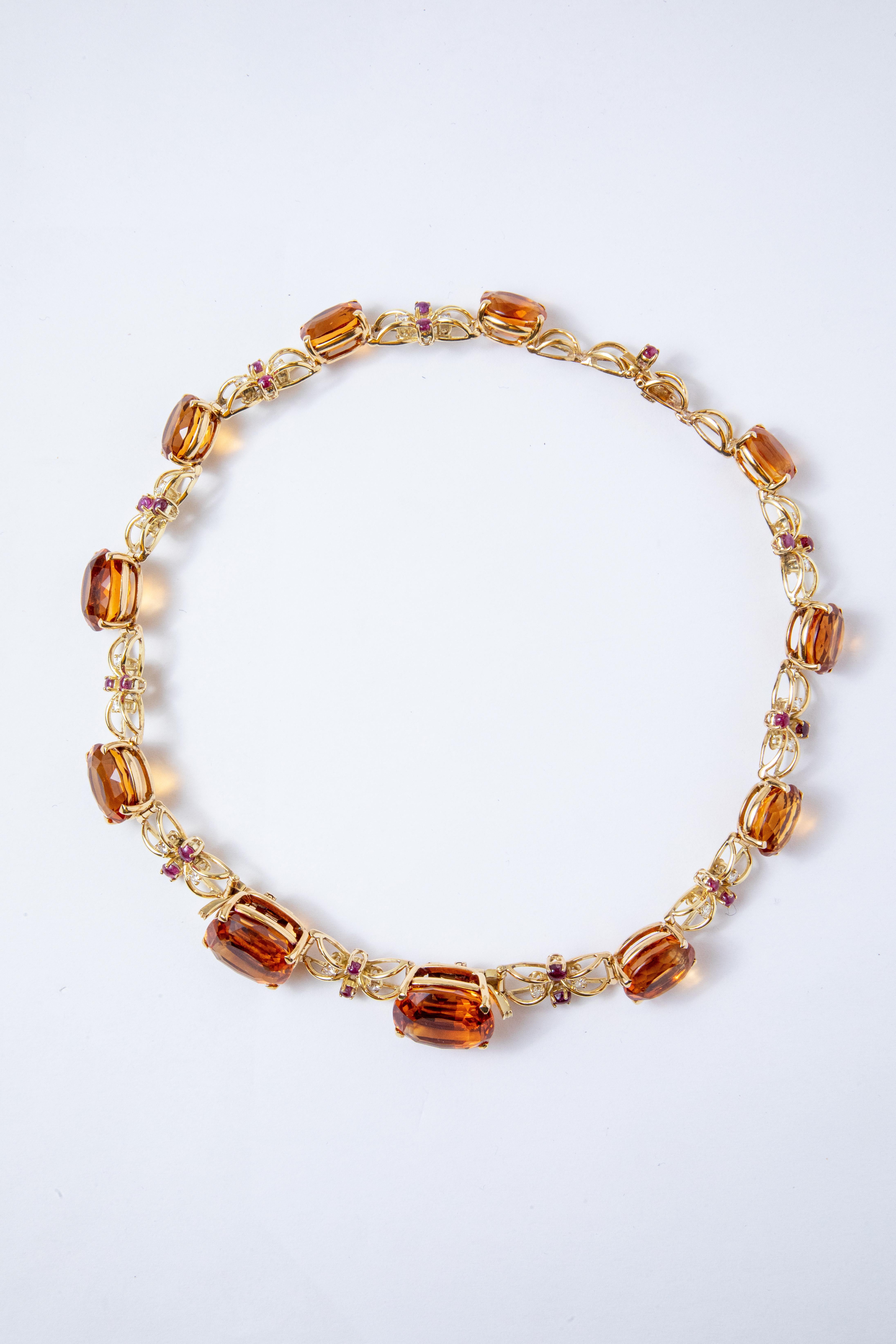 Semi-rigid choker necklace made in yellow gold with large oval-cut quartz (Citrines) alternating with intertwined links centered by two cabochon-cut rubies and two brilliant-cut diamonds.

The necklace can be divided into two bracelets and a
