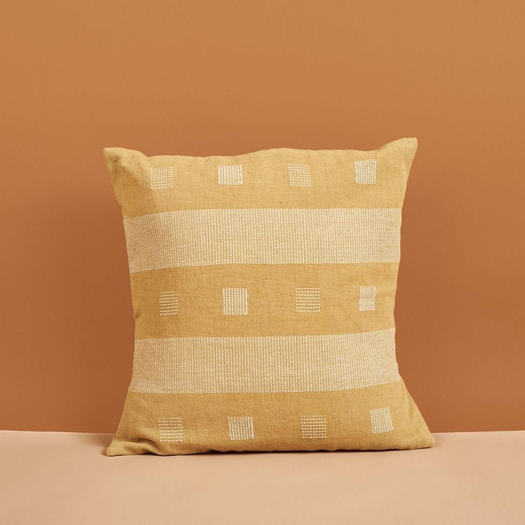 Chokor Nira Ochre Pillow is a slightly textured handwoven pillow where our artisans have skillfully created a classic pattern using an ancient weaving technique. Undyed yarn is used as a design element with the backdrop of pleasant hues of ochre