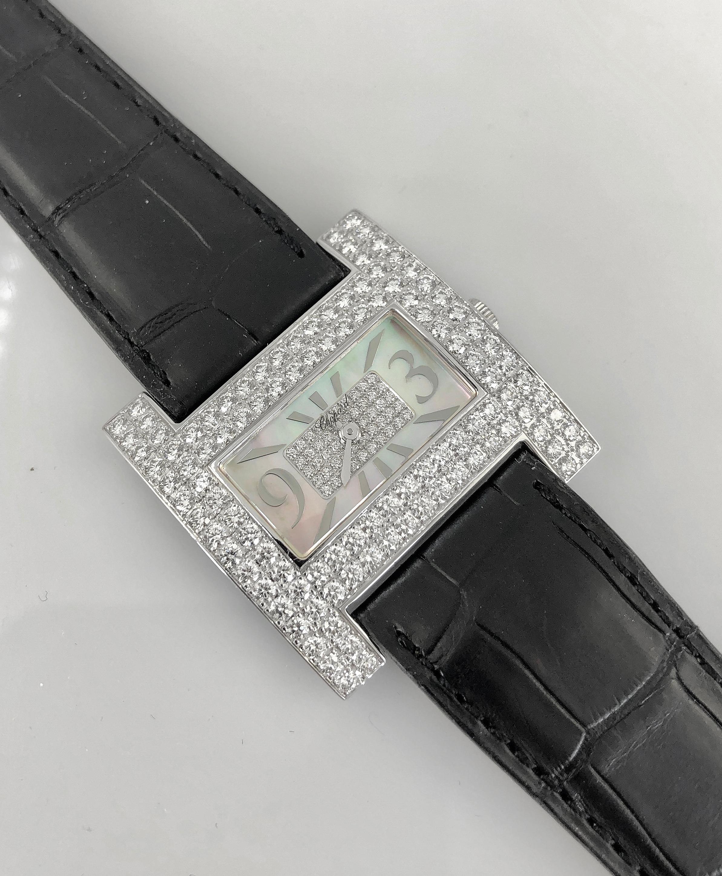 Eine raffinierte und zeitlose Chopard-Damenarmbanduhr aus 18 Karat Weißgold. Das Zifferblatt ist mit einem Diamanten im Brillantrundschliff besetzt und mit einem Zifferblatt aus Perlmutt und Diamanten versehen.
Signiert Chopard mit einem