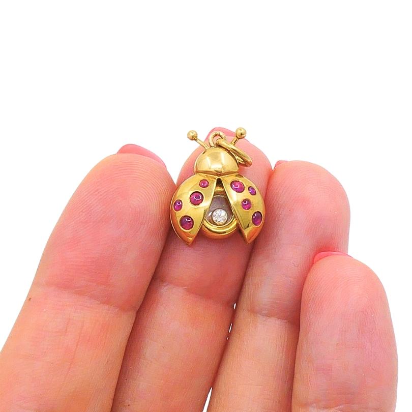 The Chopard Happy Diamond ladybird pendant / charm, crafted from 18k gold, rubies, and a diamond. The ladybird's wings are adorned with cabochon-cut rubies, and a single round brilliant-cut diamond that moves freely between two sapphire crystals.