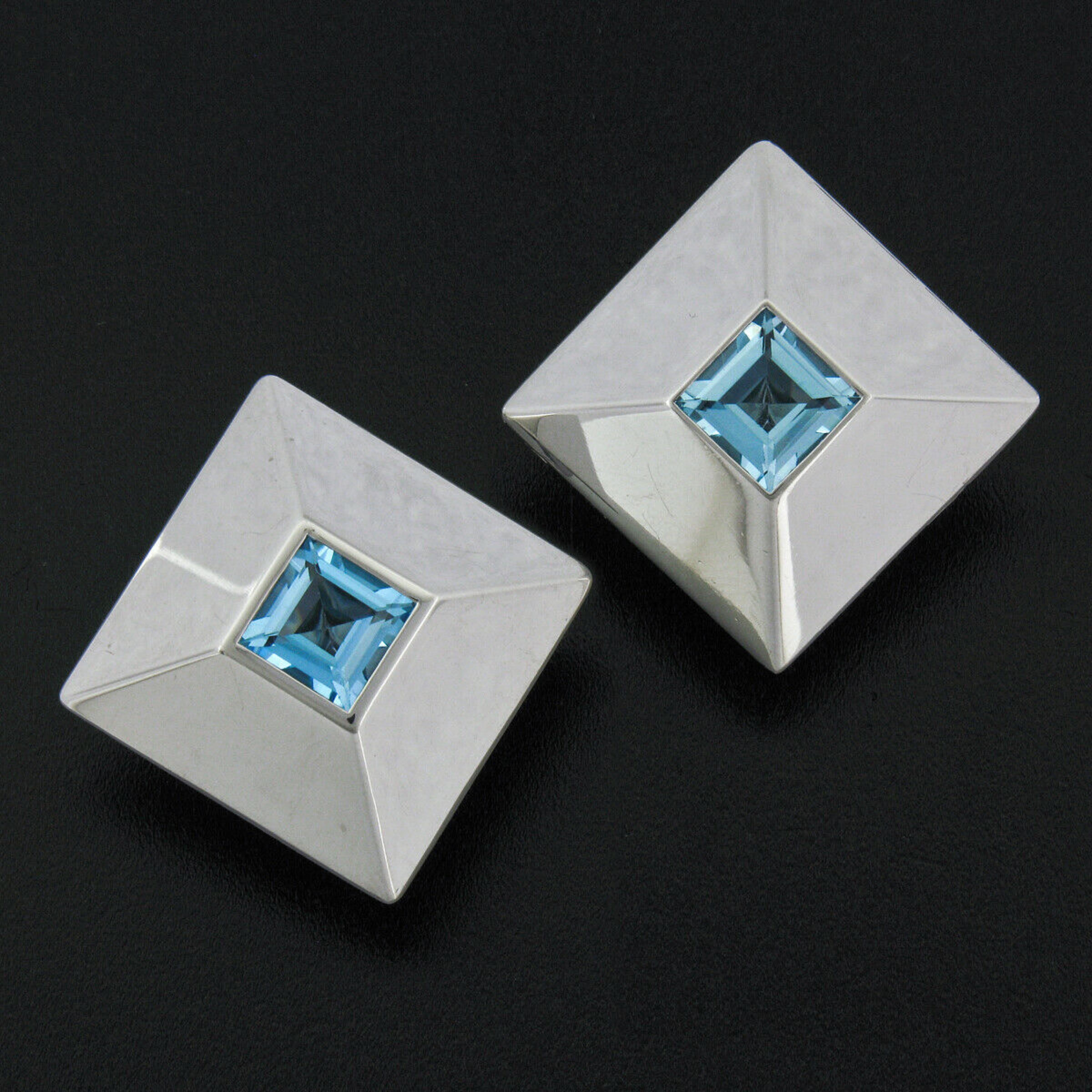 Here we have a bold and sharp looking pair of guaranteed 100% authentic Chopard earrings. The earrings feature a very classy and smooth pyramid design each bezel set at its center with a large, approximately 2.70 carat, square step cut blue topaz.