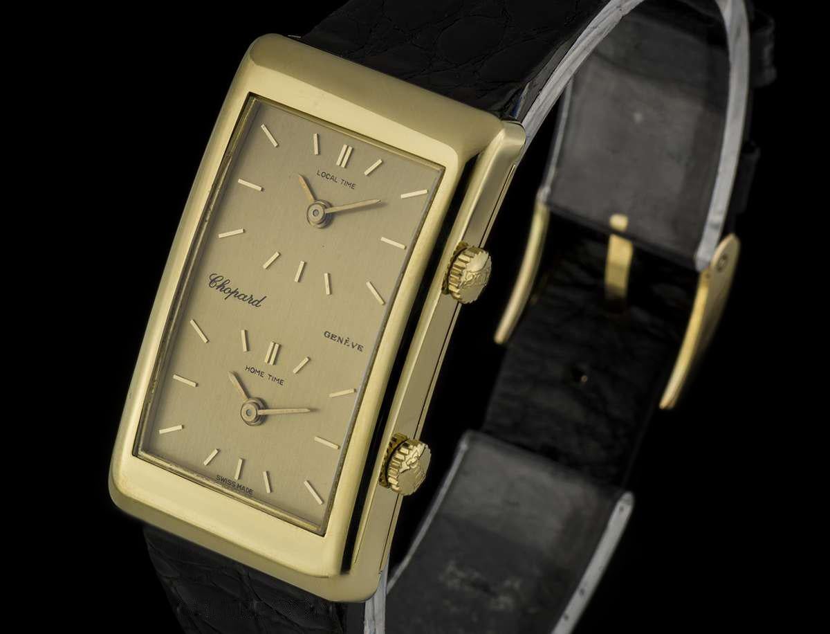 An 18k Yellow Gold Dual Time Zone Gents Wristwatch, champagne local time and home time dials with applied index batons, an 18k yellow gold fixed polished bezel, a brown leather strap (not by Chopard and not as pictured) with a gold plated pin buckle