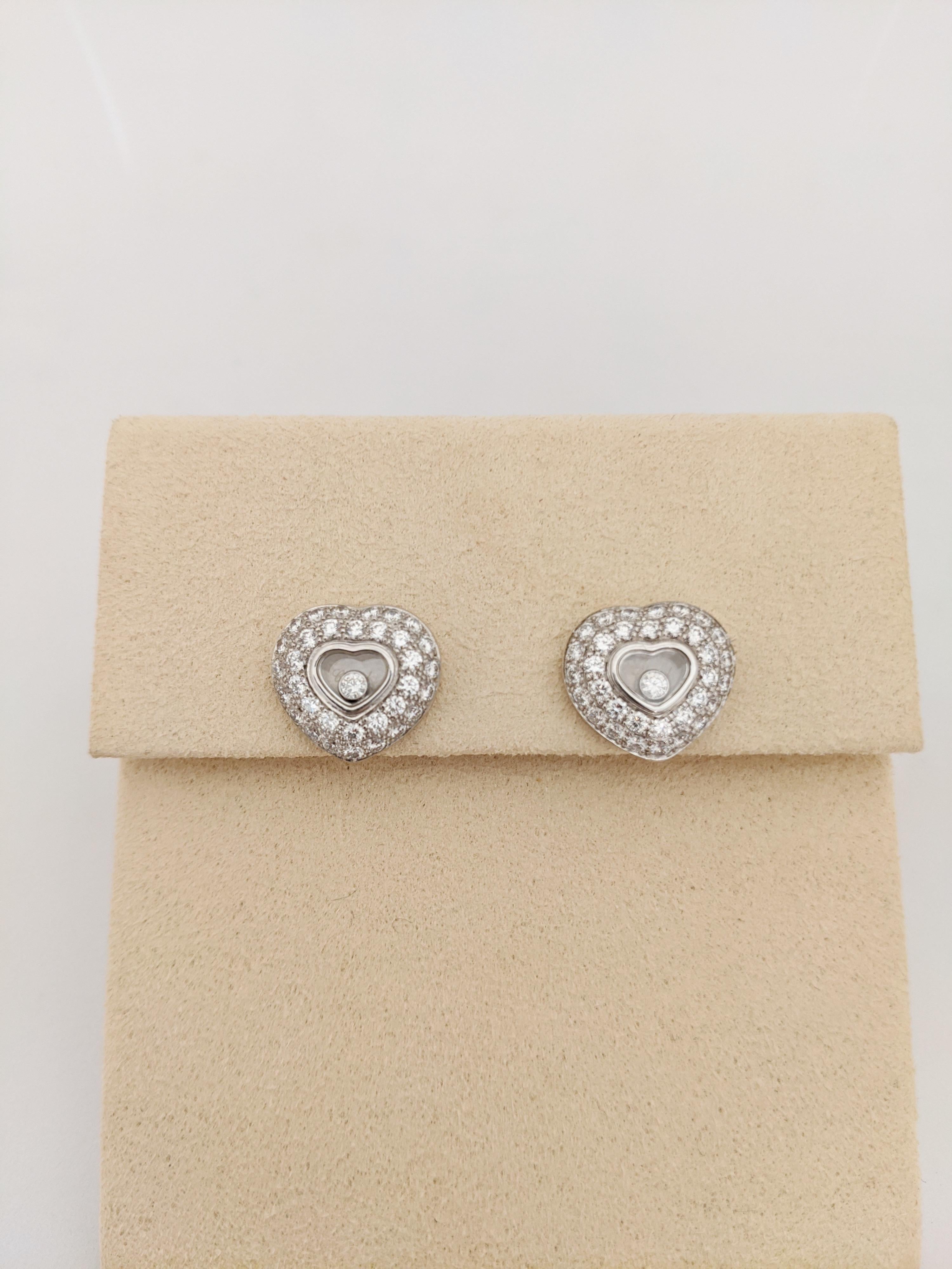 Chopard 18 KT White Gold & Diamond classic heart stud earrings. These earrings are designed with 2 rows of round brilliant pave diamonds and 1 single bezel set floating diamond in each ear. The diamond settings give the hearts a puffed heart