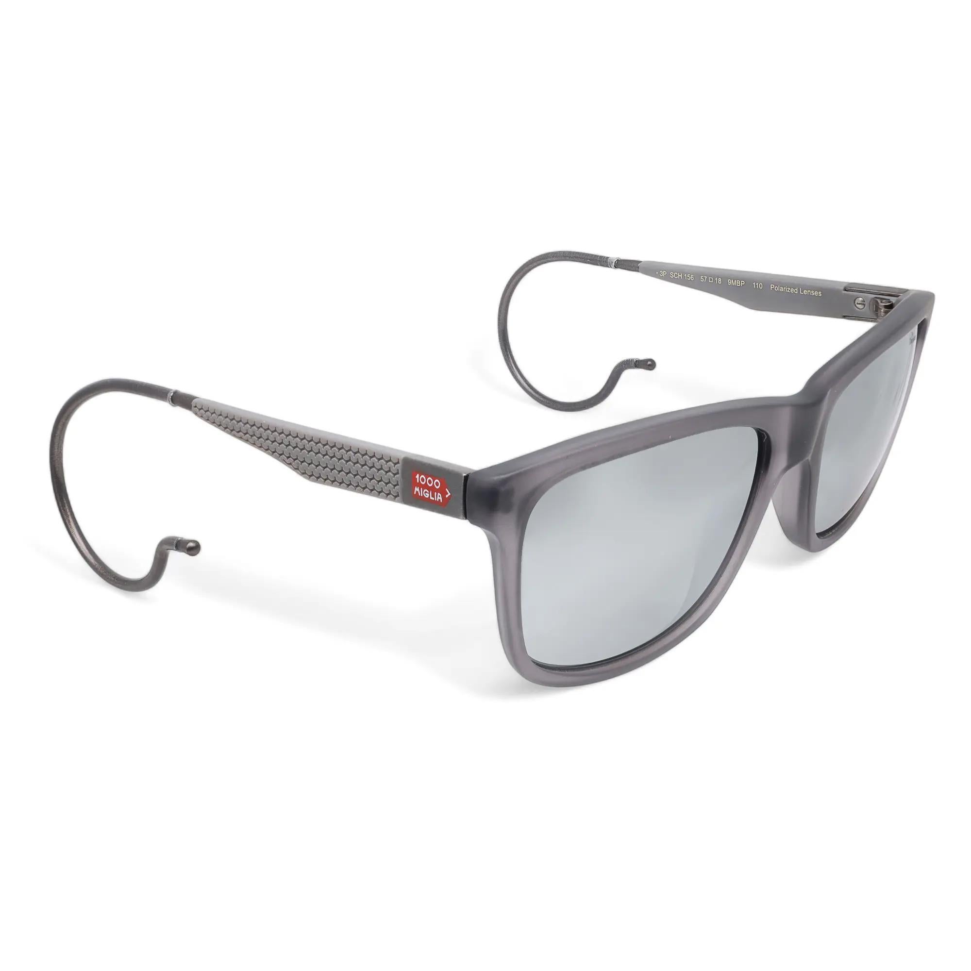Introducing the luxury unisex Chopard Sunglasses 95221-0273, perfect for street fashion. These sunglasses showcase a grey transparent acetate frame with brushed bakelite color temples and smoke flash silver polarized lenses. The arms are elegantly