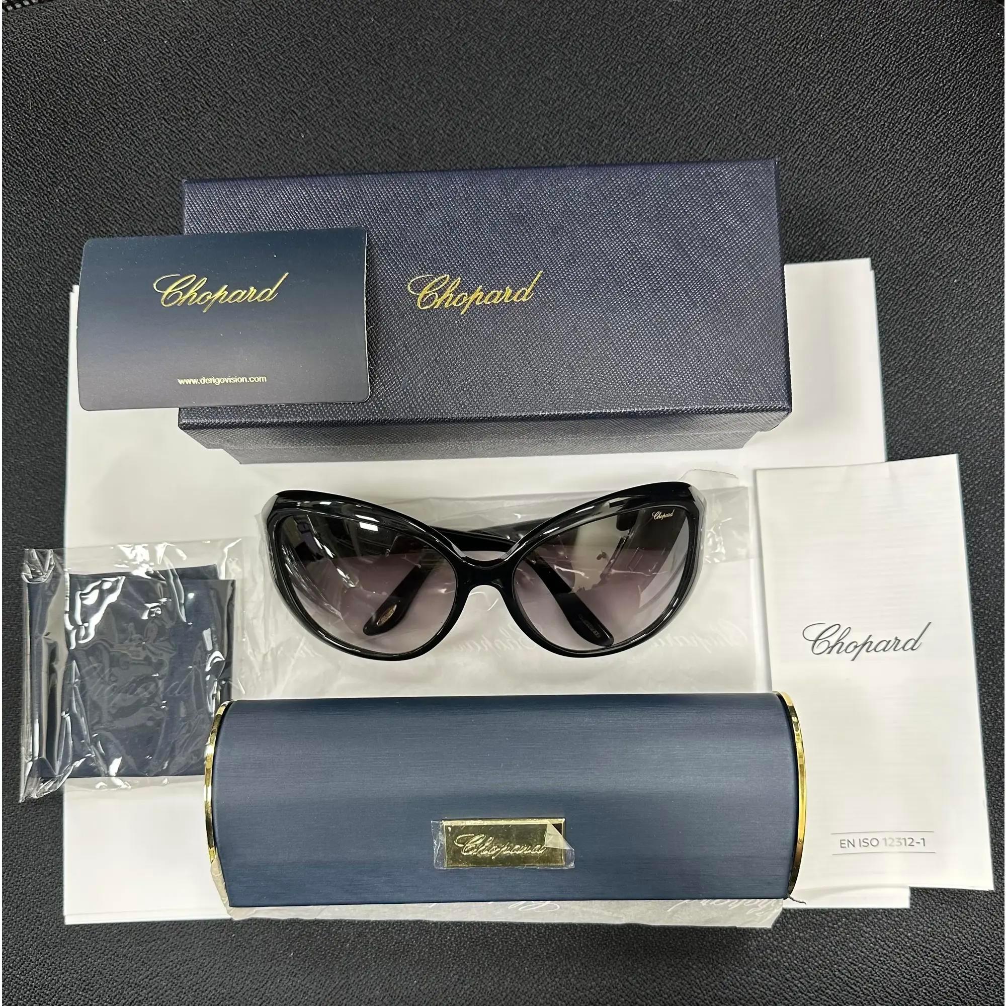 Presenting the luxury unisex Chopard Sunglasses 95221-0144, ideal for street fashion. These sunglasses feature a black acetate frame with gradient smoke lenses. The arms are adorned with the Chopard logo. The dimensions are as follows: Arm Length: 5